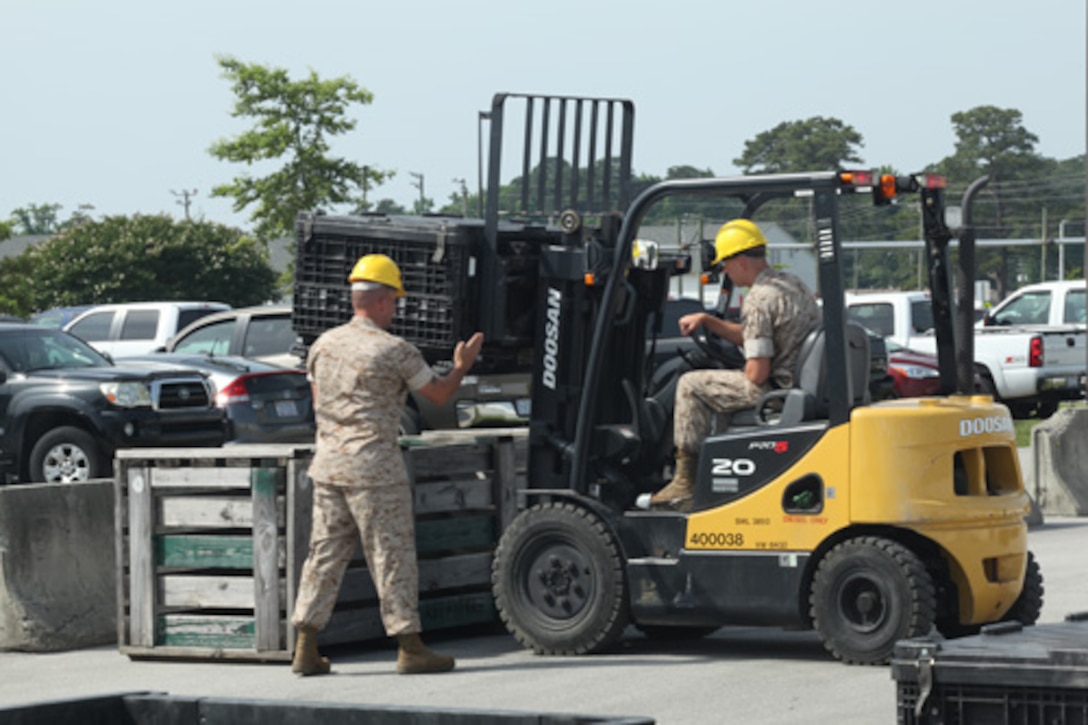 Gunnery Sergeant Danny Fisher (far left), Instructor, Enlisted Warehouse Basic Course 14-14, Ground Supply School (GSS), Marine Corps Combat Service Support Schools, instructs a Marine student on how to properly use a forklift during a practical application exercise held aboard Camp Johnson, N.C. on June 4, 2014. (Combat Camera photo by Lance Corporal Laura Mercado/ Released)