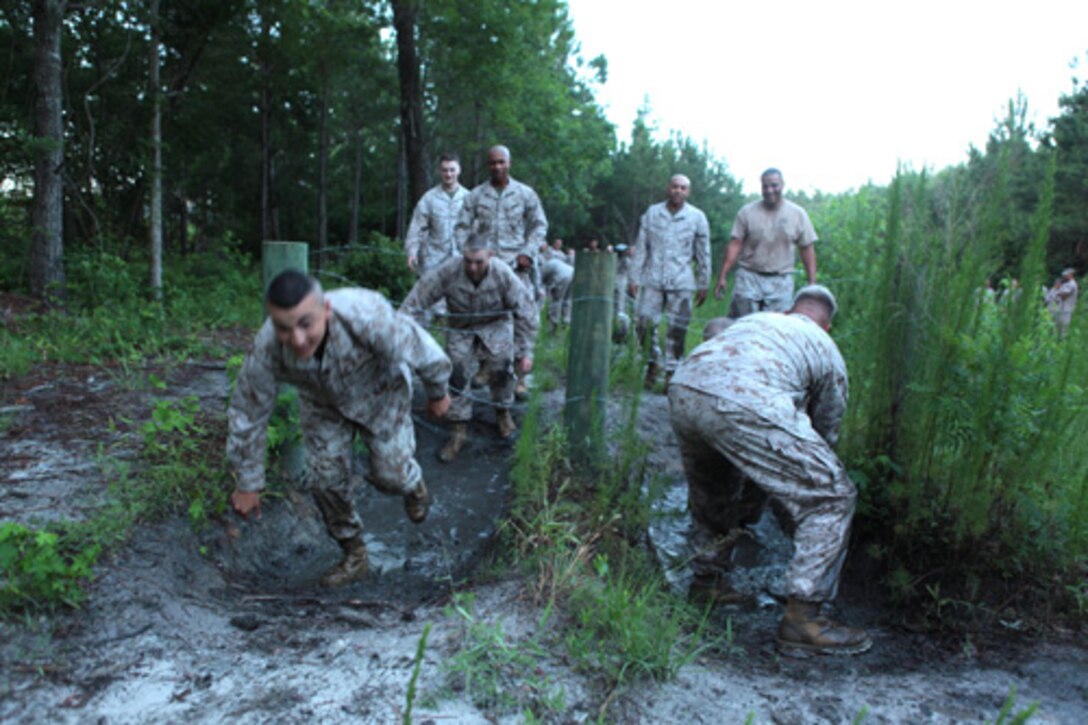 Marines with Ground Supply School (GSS), Marine Corps Combat Service Support Schools, move through mud and under constantine wire while moving through an endurance course aboard Camp Johnson, NC, June 23, 2014. Staff and student Marines of GSS participated in the team building event to build camaraderie, and cohesion within the schoolhouse. (U.S. Marine Corps Photo by Sergeant Mark E. Morrow) (Released)