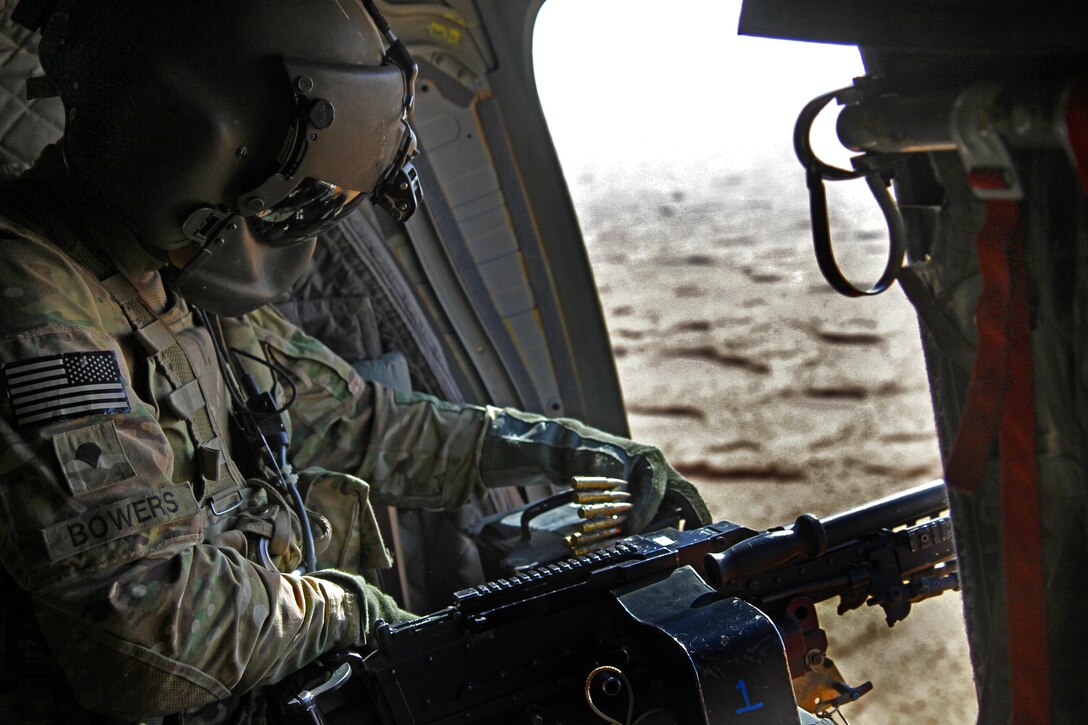 U.S. Army Spc. Matthew Bowers reloads a M240B machine gun aboard a CH-47 Chinook helicopter during aerial door gunnery at a training site in southern Kandahar province, Afghanistan, Sept. 7, 2014. Bowers is a crew chief assigned to the 1st Battalion, 52nd Aviation Regiment, 16th Combat Aviation Brigade, Task Force Flying Dragons.