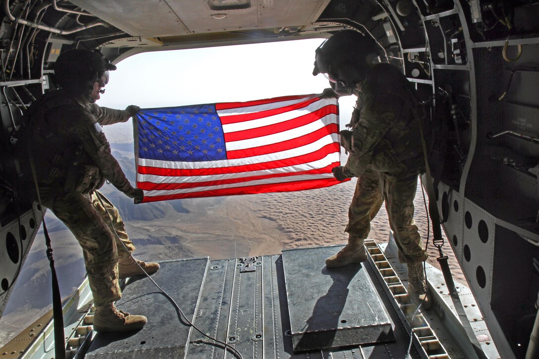 U.S. Army Staff Sgt. Corbin Long, left, and U.S. Army Spc. Matthew Bowers fly a U.S. flag from the ramp of a CH-47 Chinook helicopter at a training site in southern Kandahar province, Afghanistan, Sept. 7, 2014. Corbin and Matthew are crew chiefs assigned to the 1st Battalion, 52nd Aviation Regiment, 16th Combat Aviation Brigade, Task Force Flying Dragons.  