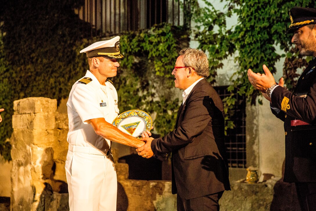 Navy Capt. Christopher J. Dennis (left), the commanding officer of Naval Air Station Sigonella, shakes hands with Marco Sinatra (right), the mayor of Vizzini, during an award ceremony for the restoration of the Cunziria, a historic district of Vizzini, Sept. 7, 2014. The “Marines Meet Verga” project was a clear example of how several different groups of volunteers of varying cultures can come together and unite for a common goal which in turn restored a significant piece of history for Vizzini.