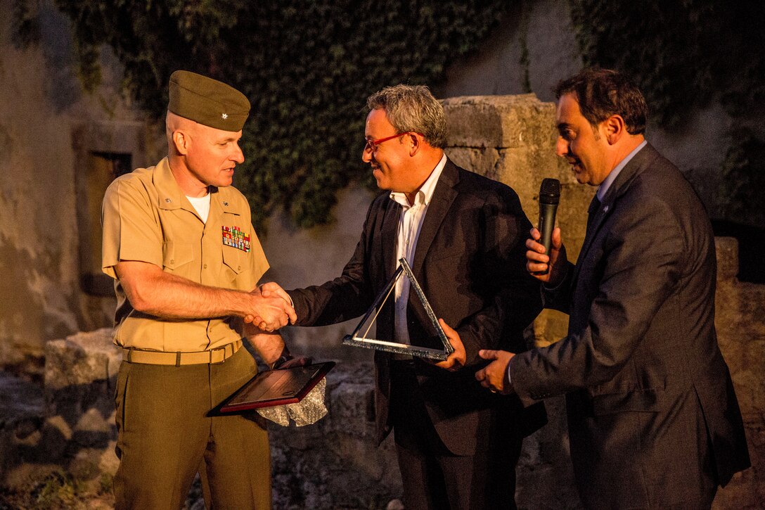 Lt. Col. William C. Stophel (left), the commanding officer of Special-Purpose Marine Air-Ground Task Force Africa 14 is awarded a plaque from Marco Sinatra, the mayor of Vizzini,  for the volunteer work the Marines and Sailors of SP-MAGTF Africa 14 did at the historic site of Cunziria, Vizzini, Sept. 7, 2014,