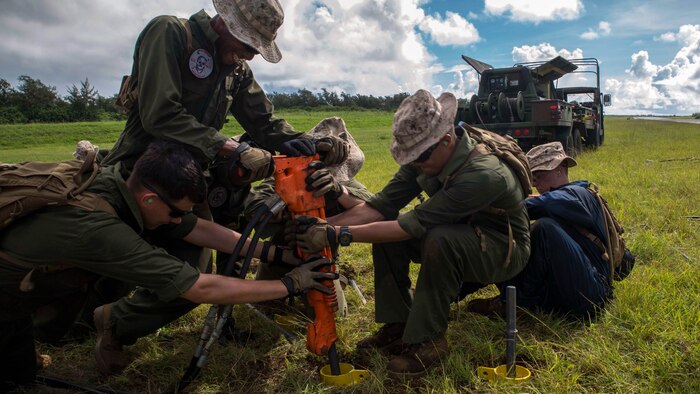 Marines with Marine Wing Support Squadrons 171 and 172, both currently assigned to Marine Aircraft Group 12, 1st Marine Aircraft Wing, III Marine Expeditionary Force, use a jackhammer to drive a stake into the ground as part of the M31 Marine Corps expeditionary arresting gear system installation in preparation for Valiant Shield 2014. Arresting gear is used to stop aircraft quickly in case they land on a short runway or experience an emergency. Valiant Shield is a biennial exercise which focuses on training that enables real-world proficiency in sustaining joint forces. 