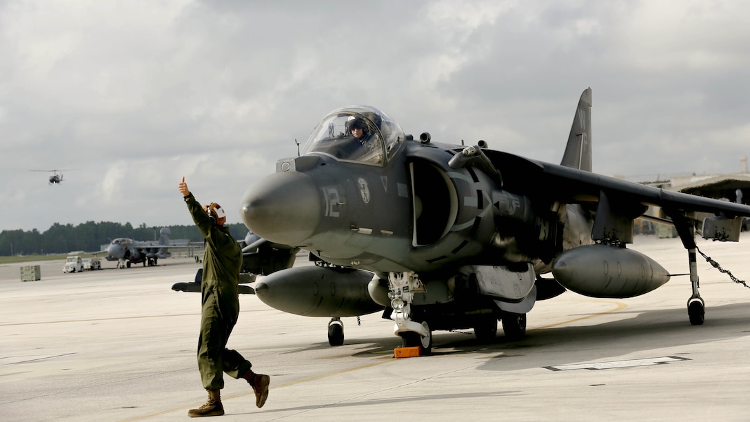 Lance Cpl. Alexander Stensland, left, signals good to go to Lt. Col. Roger T. McDuffie who is piloting an AV-8B Harrier on the flight line at Marine Corps Air Station Cherry Point, N.C., Sept. 10, 2014. Stensland is an aircraft powerline mechanic and McDuffie is the commanding officer of Marine Attack Squadron 223. Stensland is a native of Hastings, Minn.