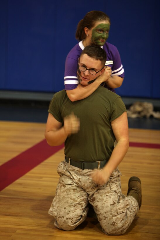 Carsey Meredith performs a choke-hold on her fiance, Lance Cpl. Nick Passopulo, as part of a Marine Corps Martial Arts demonstration during a Jane Wayne Day hosted by Marine Wing Headquarters Squadron 2 at Marine Corps Air Station Cherry Point, N.C., Sept. 12, 2014. 
Meredith is a dental assistant and Passopulo is a chemical, biological, radiological and nuclear defense specialist with MWHS-2. Both are graduates of Prince George High School, Prince George, Va. 
During the event, spouses and other extended MWHS-2 family toured portions of the air station to learn more about the day-to-day lives of their Marines. The day included familiarization classes with Marine Corps weapon systems at an Indoor Simulated Marksmanship Trainer; aircraft simulators; and a MCMAP demonstration.
