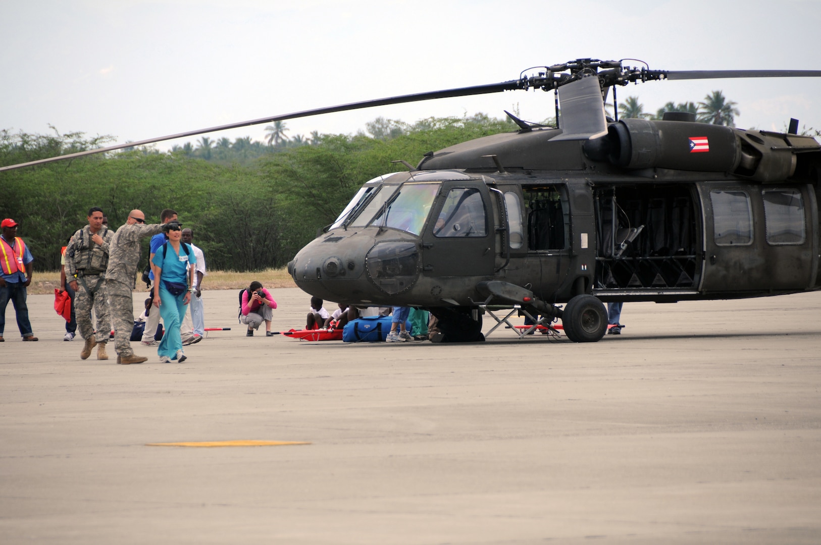 Airmen from the Kentucky National Guard's 123rd Contingency Response Group help offload wounded Haitian refugees and medical personnel from Puerto Rico National Guard UH-60 Blackhawk helicopters at the air hub in Barahona, Dominican Republic, Jan. 25, 2010.