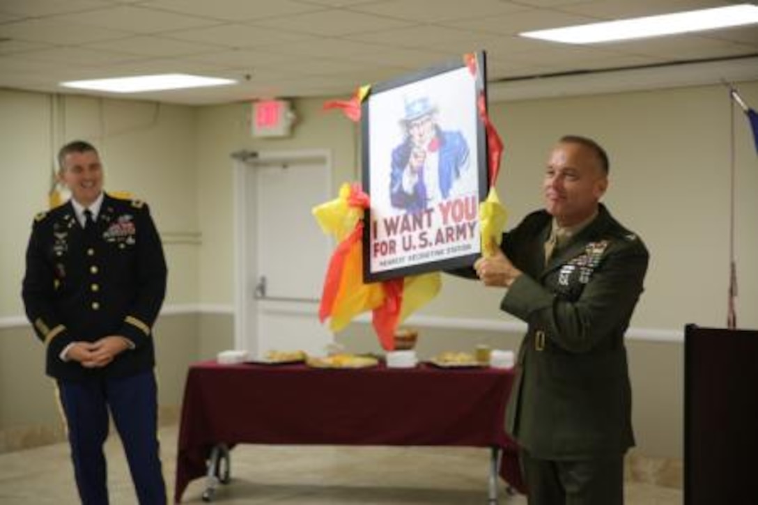Colonel Michael L. Scalise (right), commanding officer of Marine Corps Logistics Base Barstow, Calif., holds up a gift given by Col. Jonathan P. Braga (left), Fort Irwin Garrison commander, during the 2014 Military Mixer. During the social setting, the neighboring Army and Marine Corps bases exchanged rivalry jokes.


