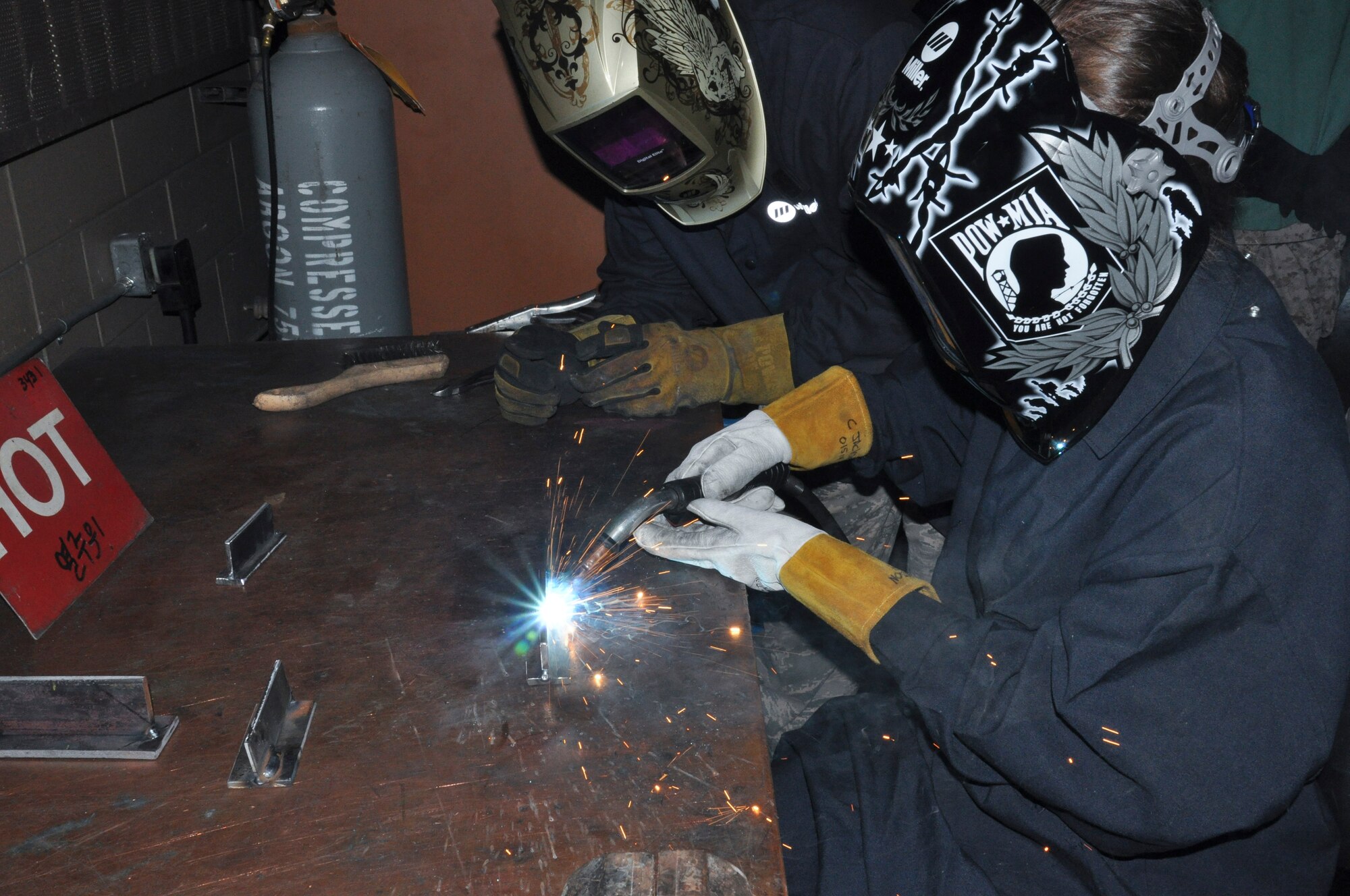 Staff Sgt. Brandon Ashby, 51st Maintenance Squadron aircraft metals technology journeyman, watches Ms. Jennifer Goodwin, Air Force Audit Agency auditor, as she welds together two metal parts, at Osan Air Base, Republic of Korea, Sept. 8, 2014.  Leadership from across Team Osan participated in the annual Mustang Immersion to develop a better understanding of what Osan Airmen are able to bring to the fight.  (U.S. Air Force photo/Capt. Robert Howard)