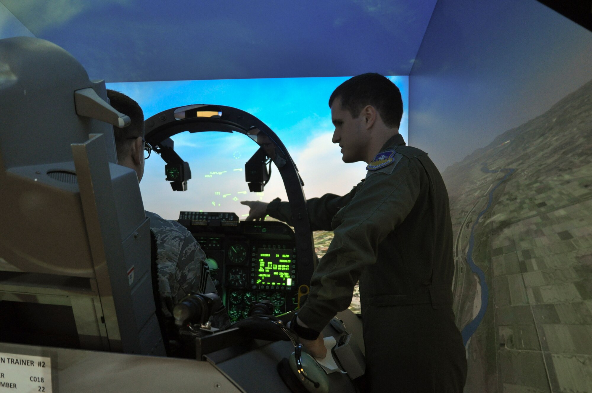 1st Lt. Eric McKernell, 25th Fighter Squadron A-10 Thunderbolt II pilot, instructs Chief Master Sgt. Ray Hickman, 51st Communications Squadron superintendent, on what the indications mean in the heads-up display of an A-10 flight simulator at Osan Air Base, Republic of Korea, Sept. 8, 2014.  Leadership from across Team Osan participated in the annual Mustang Immersion to develop a better understanding of what Osan Airmen are able to bring to the fight.  (U.S. Air Force photo/Capt. Robert Howard)