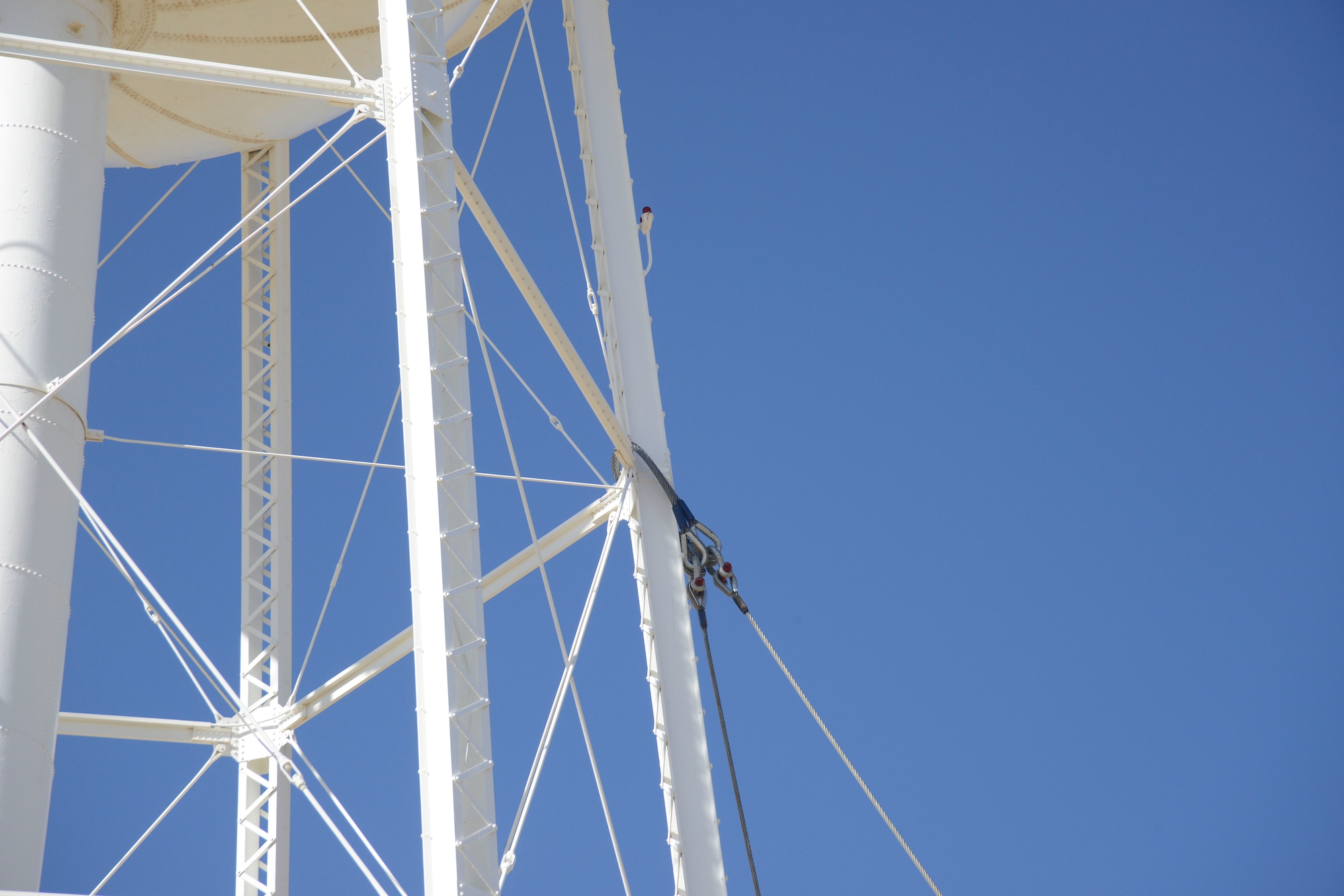 Cables were attached to the tower and to an excavator, which pulled it down after one leg and the center column were cut to weaken the structure. (U.S. Air Force photo by Kenji Thuloweit) 

