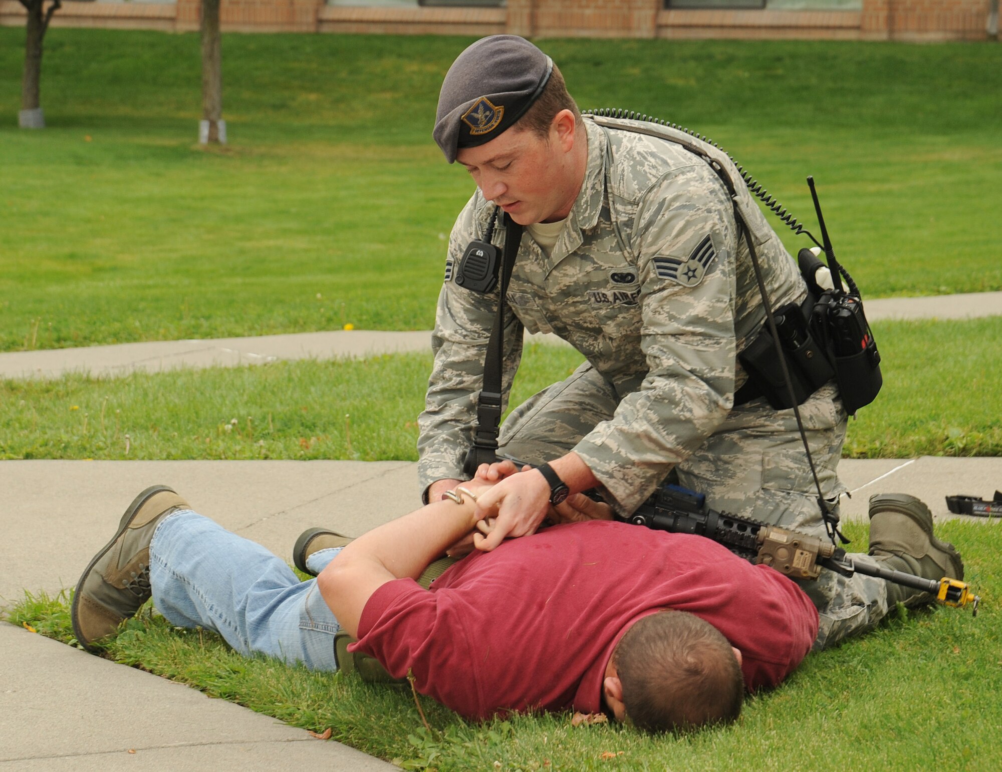 Senior Airman Dustin Kimball, 92nd Security Forces Squadron patrolman, handcuffs Tech. Sgt. Derek Washburn, 92nd Security Forces flight sergeant, during an active shooter exercise at Fairchild Air Force Base, Washington, Sept. 16, 2014. Run-hide-fight is the response technique for all base personnel to determine how to properly react in an active shooter situation. Continuous training and preparedness is integral to ensuring base safety. (U.S. Air Force photo by Staff Sgt. Samantha Krolikowski/Released)