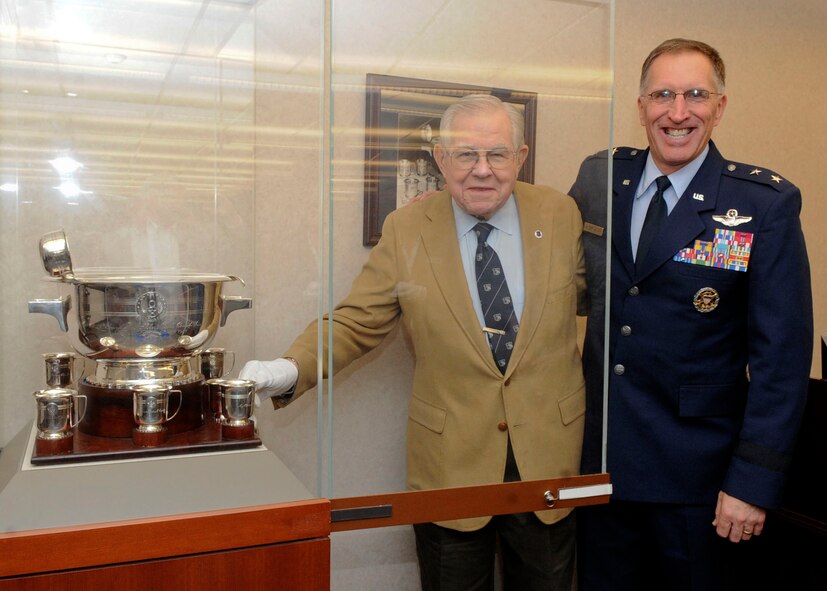 Retired Lt. Gen. Edgar Harris, former Eighth Air Force commander, and Maj. Gen. Scott Vander Hamm, Eighth Air Force commander, place the sixth Eaker cup in a display cabinet on Barksdale Air Force Base, La., Sept. 15, 2014. The cup was donated by Dean Boles, veteran, after he read about the history of the Eaker Bowl and cups from an article published in 2007. (U.S. Air Force photo/Senior Airman Kristin High)