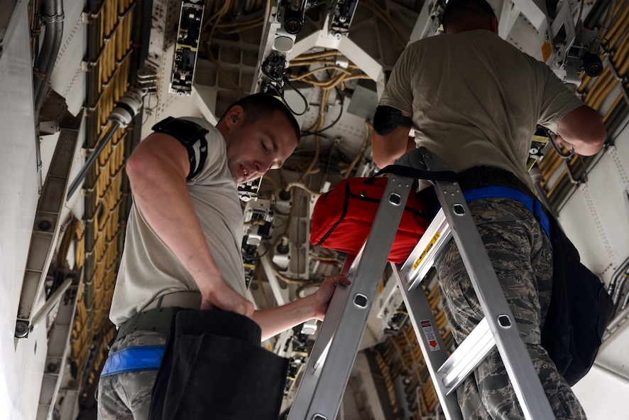 U.S. Air Force Senior Airman Christopher Sanders, left, and Airman 1st Class Timothy Hamilton, both 7th Aircraft Maintenance Squadron weapons load crewmembers, perform bomb rack preparations during the Global Strike Challenge Sept. 11, 2014, at Dyess Air Force Base, Texas. In this competition, points were awarded based on how close the bomb was placed to the target, how accurate the bomb was timed to drop and the communication skills employed by participants. (U.S. Air Force photo by Airman 1st Class Kedesha Pennant/Released)