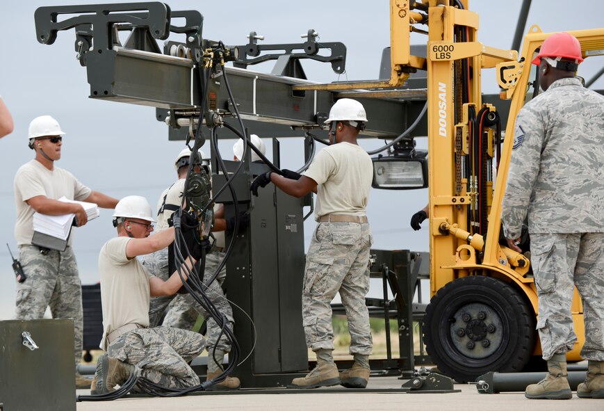 U.S. Air Force Airmen from the 7th Munitions Squadron gather parts to construct a munitions assembly conveyor as an inspector watches during the Global Strike Challenge Sept. 11, 2014, at Dyess Air Force Base, Texas. The objectives of the Global Strike Challenge competition are to demonstrate bomber, missile, helicopter, maintenance and security forces capabilities. Other goals are to test and develop equipment, tactics, techniques, procedures and enhance esprit de corps by recognizing crew, team, and individual and unit professionalism. (U.S. Air Force photo by Airman 1st Class Kedesha Pennant/Released)
