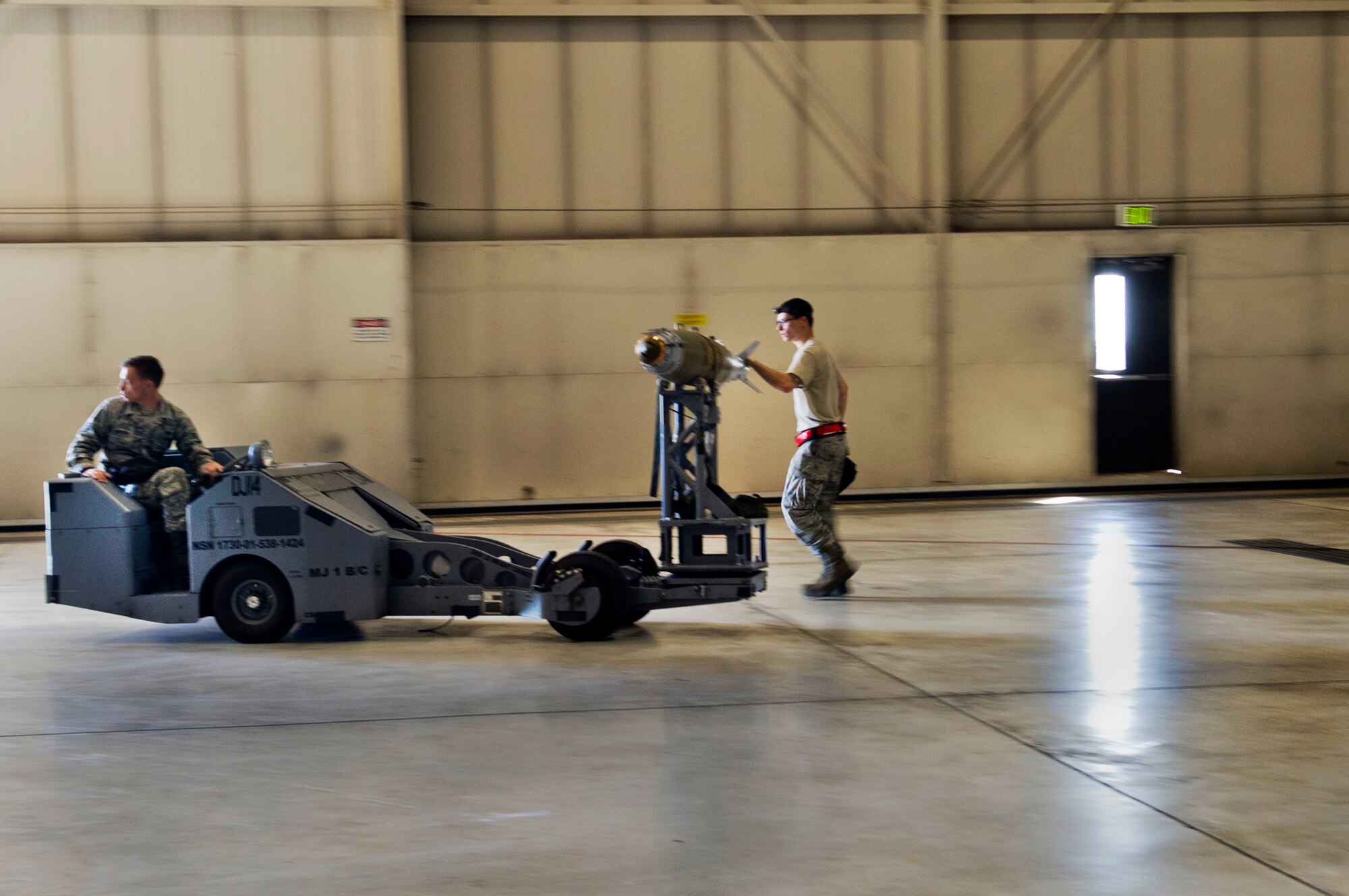 Senior Airman Andrew Grimes, 5th Aircraft Maintenance Squadron weapons load crew member, guides a joint direct attack GBU-38 munition while Airman 1st Class Michael Page, 5th AMXS weapons load crew member, drives a  MJ-1 Jammer on Minot Air Force Base, N.D., Sept. 5, 2014. The load crew is evaluated on how quickly they load munitions onto a B-52H Stratofortress and how many discrepancies are found.  (U.S. Air Force photo/Senior Airman Brittany Y. Bateman)