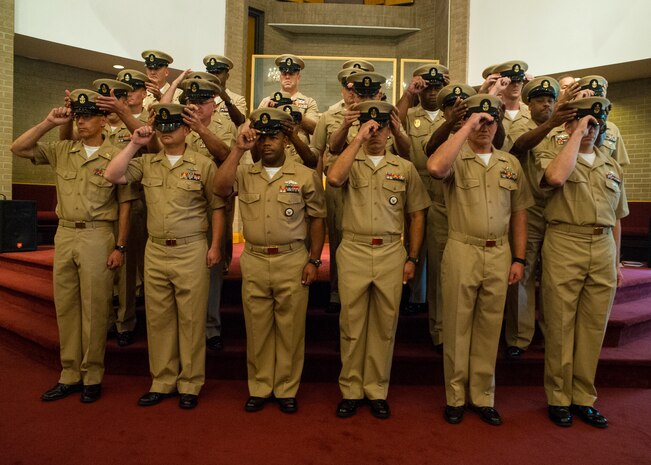 Chief petty officers from several LowCountry commands don their new covers with the help of their sponsors Sept. 16, 2014, at the All Saints Chapel on Joint Base Charleston, S.C. The pinning ceremony marks the culmination of hard work and dedicated service, and begins the next step of their Navy career as deckplate leaders. (U.S. Air Force photo/Staff Sgt. William A. O’Brien)