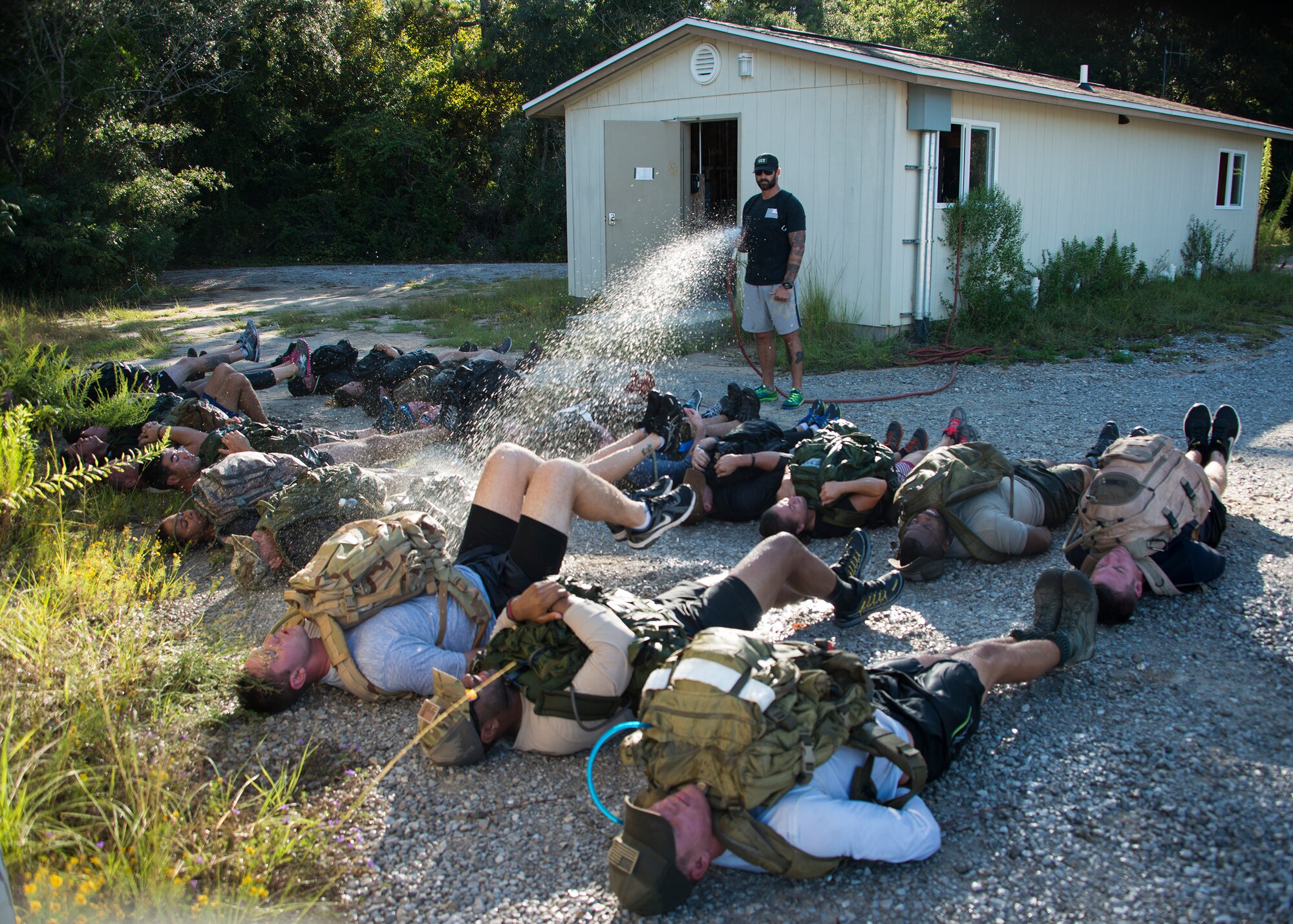 The instructor sprays the participants with a waterhose while they perform flutter kicks during the GORUCK Cohesion Challenge Sept. 11, at Eglin Air Force Base, Fla.  This elite team-building event, led by a Special Forces veteran, featured military inspired challenges and missions.  Only 24 out of the original 27 completed all obstacles.  Eglin is the fifth base to complete the Team Cohesion Challenge, which is modeled after special operations training.  (U.S. Air Force photo/Tech. Sgt. Jasmin Taylor)