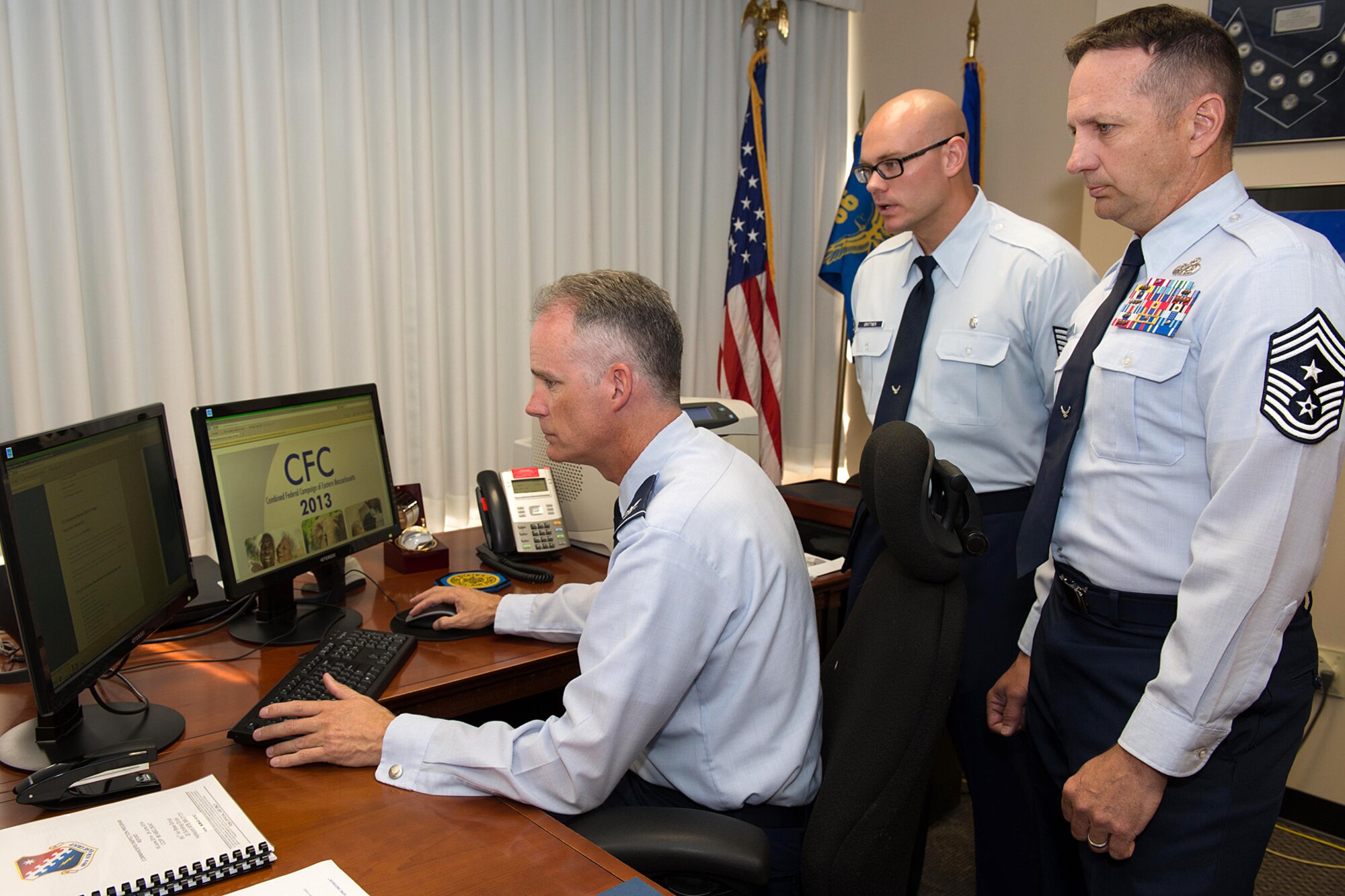 66th Air Base Group Commander Col. Michael A. Vogel completes his Combined Federal Campaign online pledge form from his office as Tech. Sgt. Scott Grittner, CFC base representative, and Command Chief Master Sgt. Craig A. Poling look on Sept. 15. The Combined Federal Campaign is scheduled to begin Sept. 22, continuing through Nov. 21. (U.S. Air Force photo by Mark Herlihy)