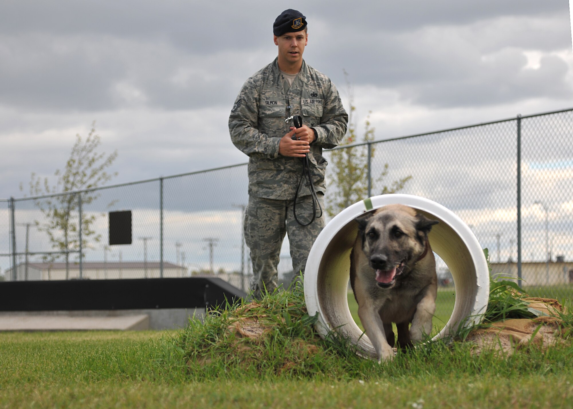 Staff Sgt. Brett Silmon, 319th Security Forces Squadron military working dog handler, commands his K9 partner, Arco, to run through a tunnel during a training course exercise on Sept. 11, 2014, on Grand Forks Air Force Base, N.D. Recently awarded the Iron Dog award during the North Dakota Peace Officers Association’s K9 Challenge, Arco keeps fit by maneuvering through a dog course. (U.S. Air Force photo/Senior Airman Xavier Navarro)