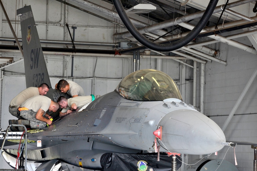 Four U.S. Air Force Airmen assigned to the 20th Component Maintenance Squadron, conduct a fuel tank inspection after installing a wing on an F-16CM Fighting Falcon at Shaw Air Force Base, S.C., Sept. 16, 2014. The inspection was conducted after the wing was installed to ensure the fuel tank was not damaged during the process. (U.S. Air Force photo by Airman 1st Class Jonathan Bass/Released)