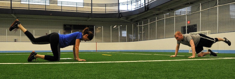 Leah Melquist (left), Health and Wellness Center health promotion manager, and Senior Airman Morgan Mesa, 69th Reconnaissance aircraft structural maintenance apprentice, perform kickbacks at the running clinic Sept. 2, 2014, on Grand Forks Air Force Base, N.D. Kickbacks are used to strengthen core muscles and gluteal muscles. Keeping core and leg muscles strong minimizes the risk of injury. (U.S. Air Force photo/Airman 1st Class Bonnie Grantham)