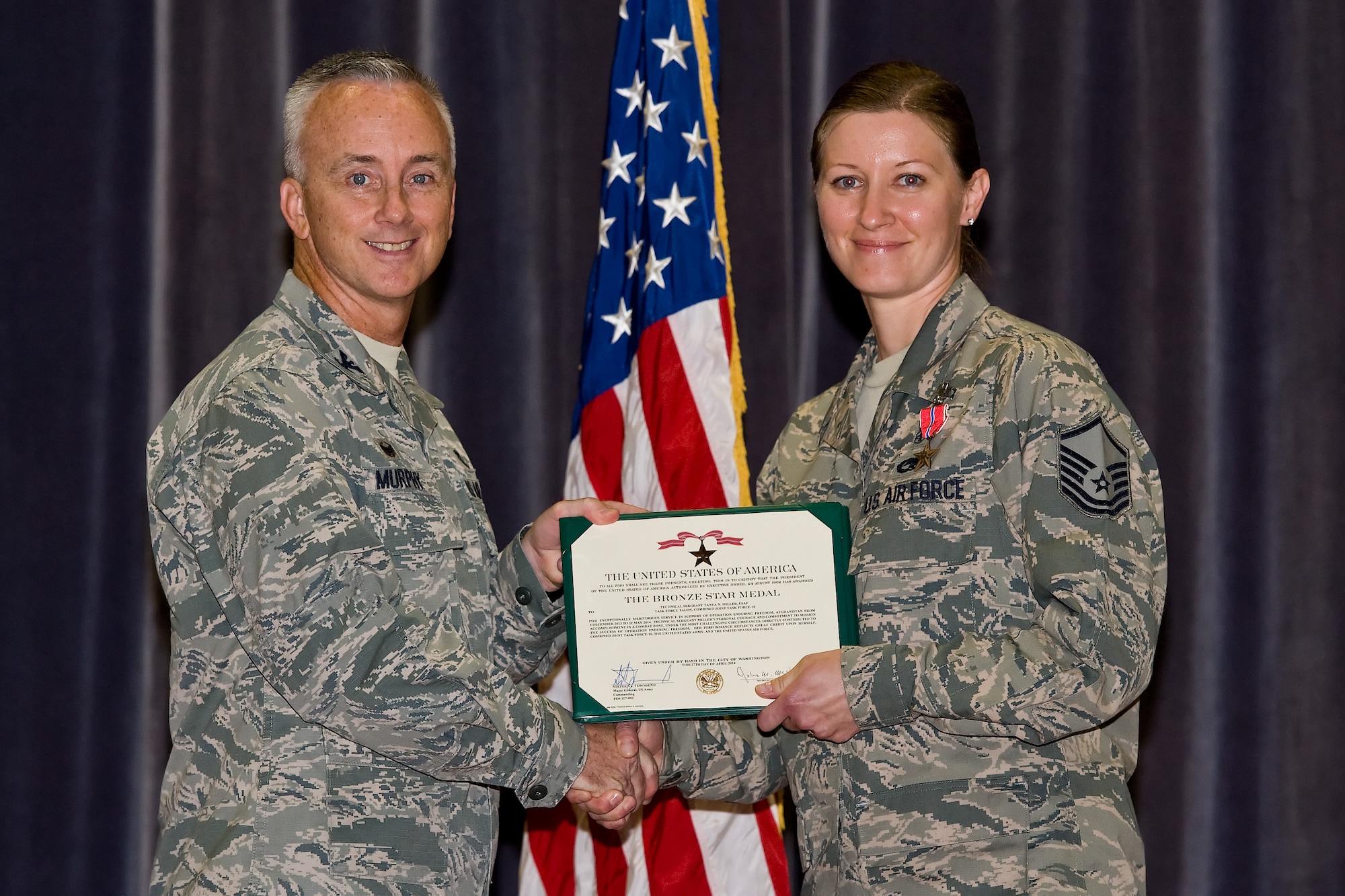 Col. Kevin Murphy, 436th Medical Group commander, left, presents Master Sgt. Tanya Miller, 436th Medical Operations Squadron, the Bronze Star Medal during commander's call Sept. 9, 2014, at the base theater on Dover Air Force Base, Del. Miller distinguished herself by exceptionally meritorious wartime service as the Combat Stress Control Clinic NCO in Charge for 1-502 Infantry Battalion, 2nd Brigade Combat Team (Task Force Strike), 101st Airborne Division (Air Assault), Forward Operating Base Fenty, Afghanistan, from Dec. 5, 2013 to May 21, 2014. (U.S. Air Force photo by Roland Balik)