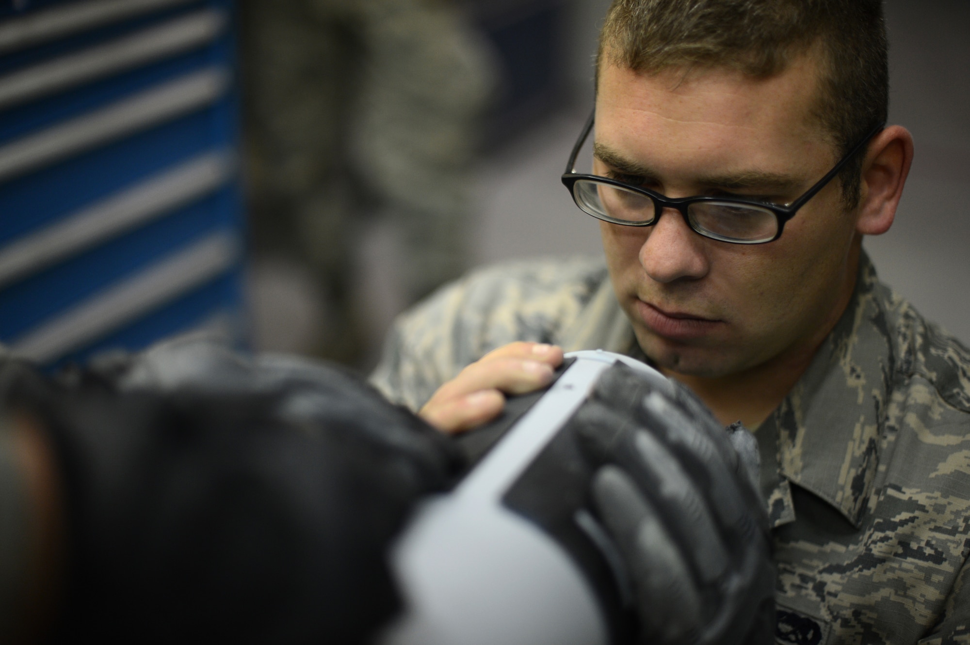 U.S. Air Force Senior Airman Daniel Devincenzo, a 52nd Equipment Maintenance Squadron precision guided munitions technician and native of Parsippany, N.J., holds a stencil in place while painting an AIM-9 sidewinder missile on Spangdahlem Air Base, Germany, Sept. 10, 2014. Airmen use stencils to precisely mark the missile with part numbers for inventory control and designated areas for mechanical parts. (U.S. Air Force photo by Senior Airman Gustavo Castillo/Released) 