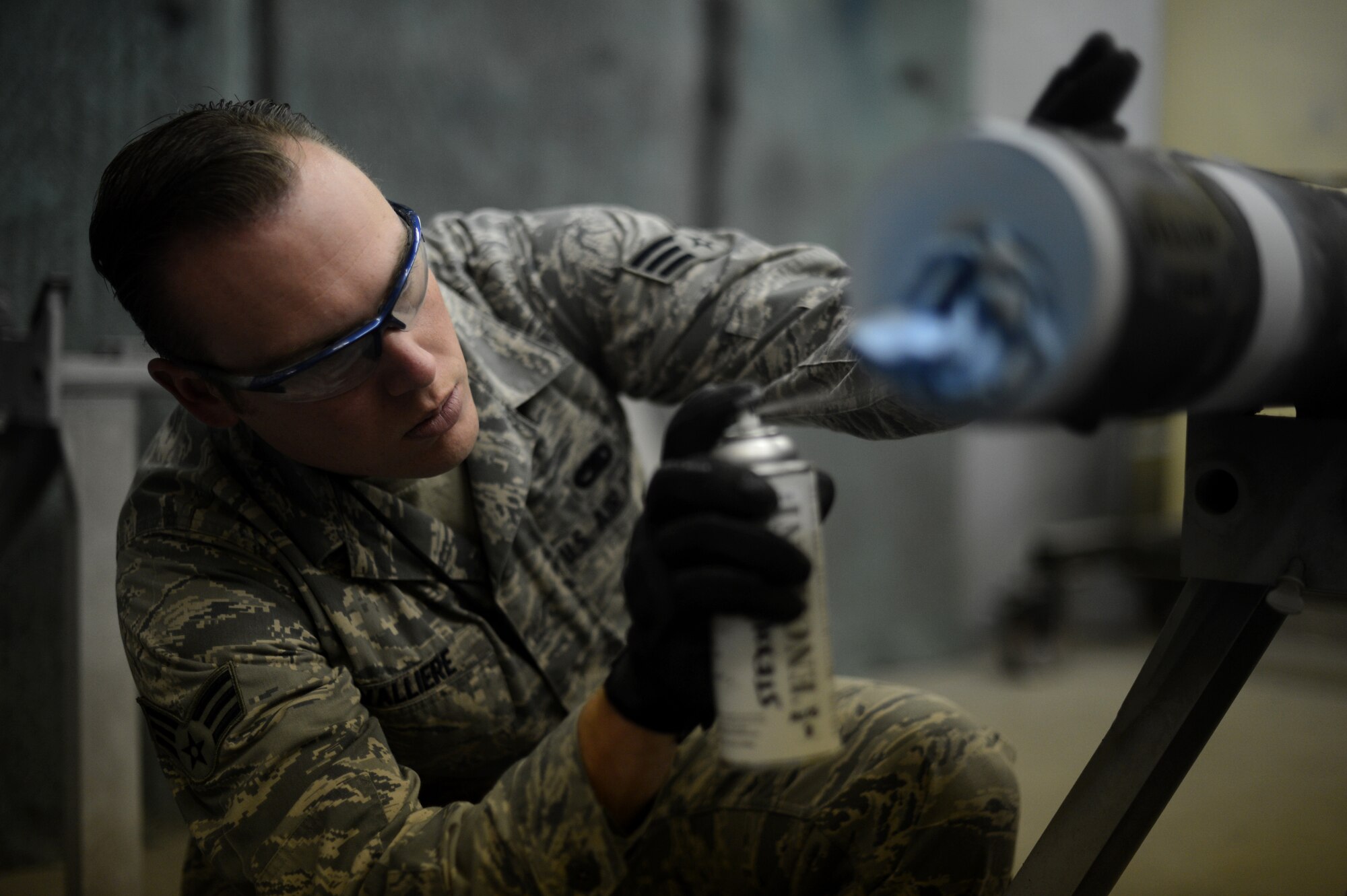 U.S. Air Force Senior Airman Anthony Valliere, a 52nd Equipment Maintenance Squadron precision guided munitions technician and native of Chandler, Ariz., covers overspray from markings on an AIM-9 sidewinder missile on Spangdahlem Air Base, Germany, Sept. 10, 2014. Airmen from the 52nd EMS maintain and deliver combat airpower to the flightline through several types of munitions. (U.S. Air Force photo by Senior Airman Gustavo Castillo/Released) 