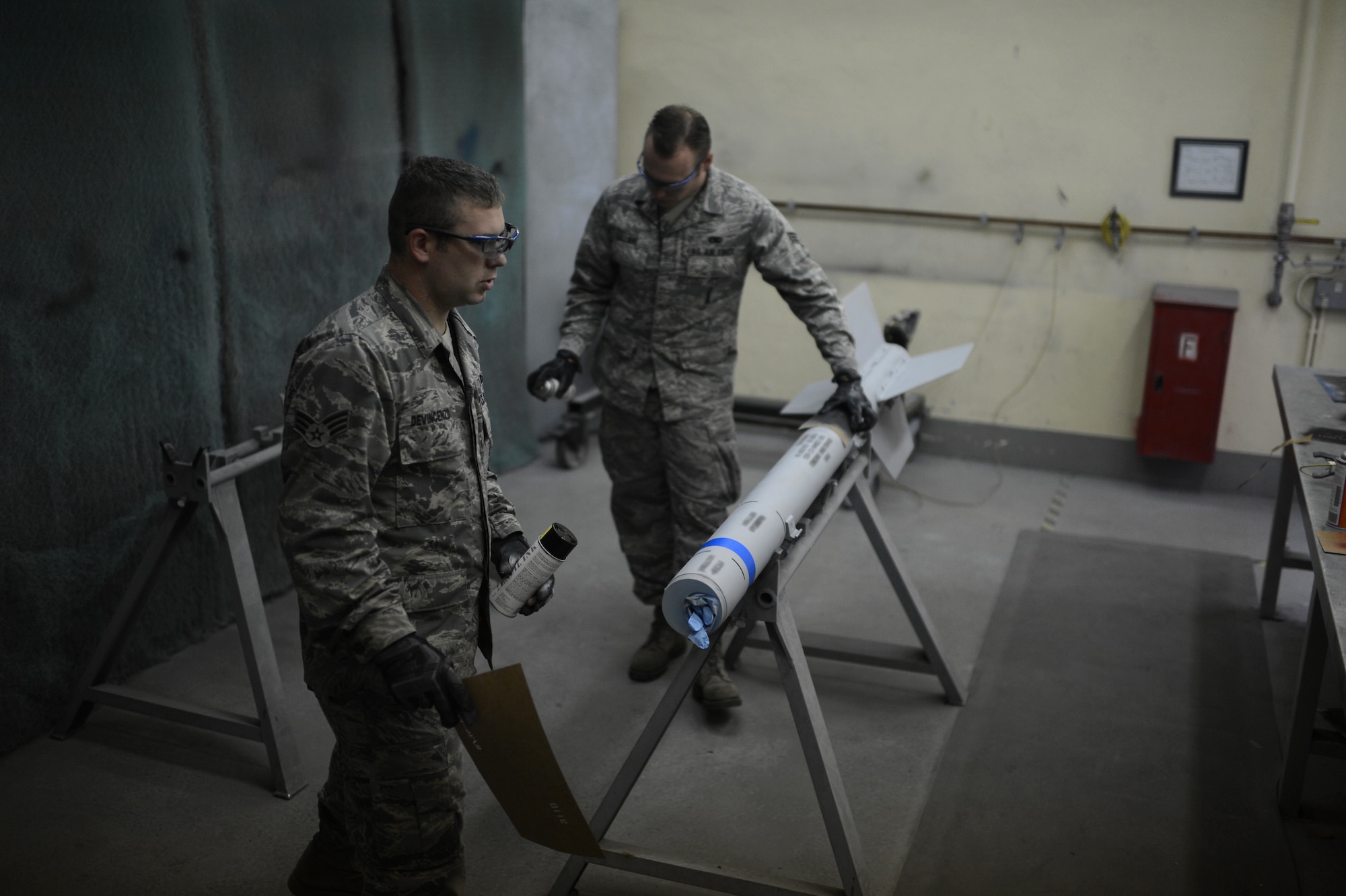 U.S. Air Force Senior Airmen Daniel Devincenzo and Senior Airman Anthony Valliere, 52nd Equipment Maintenance Squadron precision guided munitions technicians and natives of Parsippany, N.J., and Chandler, Ariz. respectively, apply the finishing markings on an AIM-9 sidewinder missile on Spangdahlem Air Base, Germany, Sept. 10, 2014. Airmen use training rounds, which are hollow shells with no electronic components and marked with blue rings, to practice real-world operations without handling or damaging live munitions. (U.S. Air Force photo by Senior Airman Gustavo Castillo/Released) 