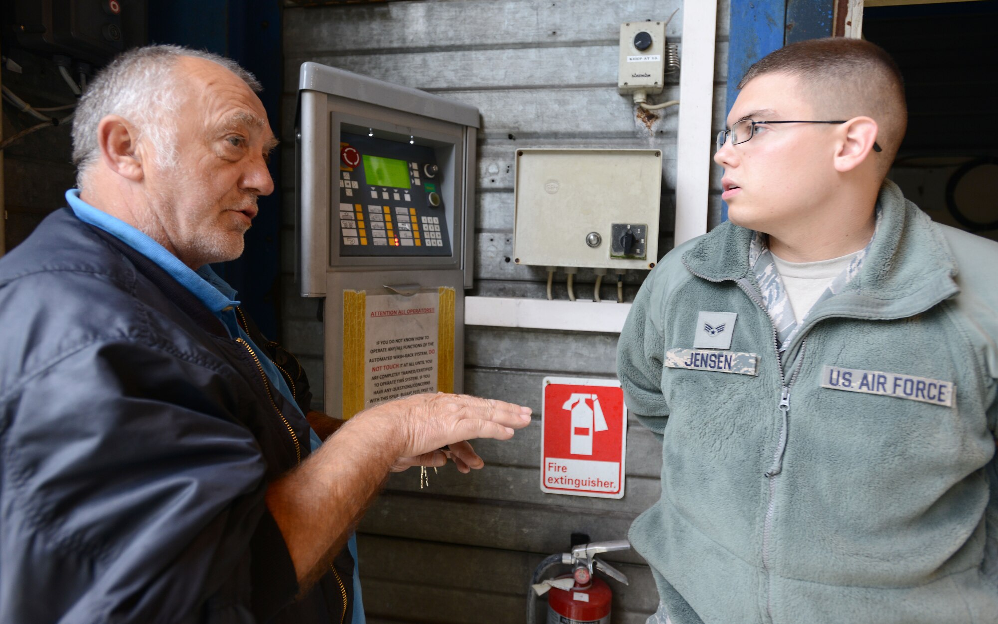 Guenter Spletter explains the wash rack operating controls to Senior Airman Matthew Jensen, both 86th Vehicle Readiness Squadron vehicle operators, at Ramstein Air Base, Germany, Sept. 12, 2014. If not operated correctly, patrons could potentially damage the wash rack system or a government motor vehicle, stopping both items from being used to support the local mission. (U.S. Air Force photo/Senior Airman Timothy Moore)