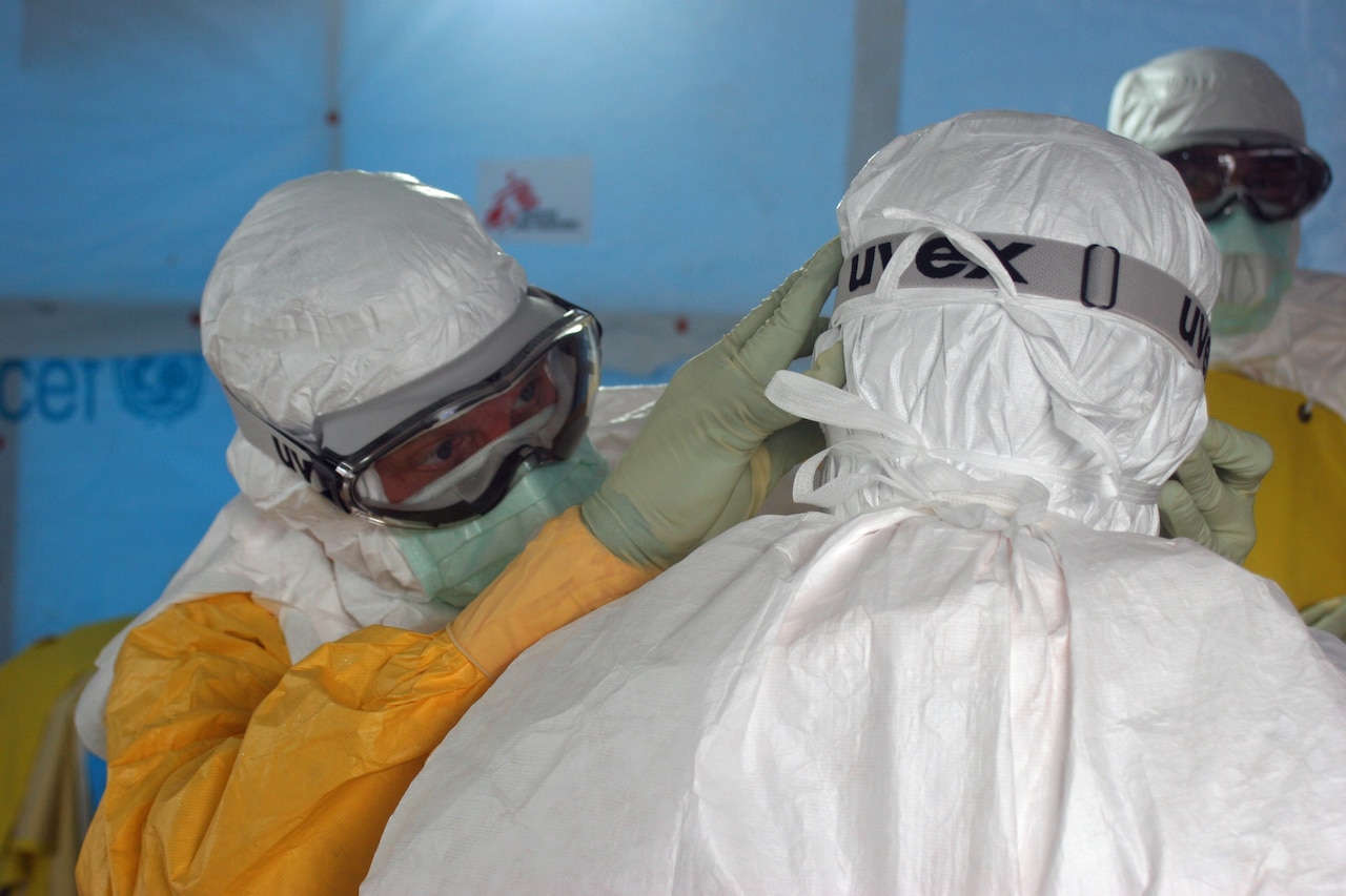 This image was captured in Monrovia, Liberia’s capital city, during the 2014 West African Ebola virus disease outbreak that also affected Sierra Leone, Guinea and Nigeria. Here Dr. Joel Montgomery, team lead for the U.S. Centers for Disease Control and Prevention Ebola Response Team in Liberia, is dressed in his personal protective equipment while adjusting a colleague’s PPE before entering the Ebola treatment unit, which opened on August 17, 2014. This treatment unit is staffed and operated by members of Médecins Sans Frontières (MSF), or Doctors Without Borders. CDC photo by Athalia Christie
