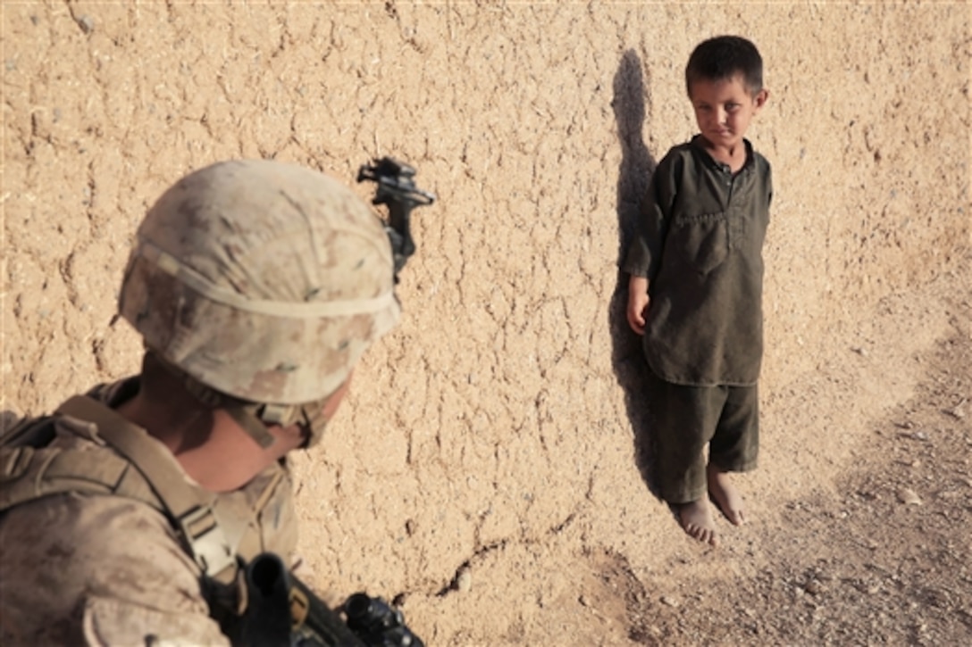 U.S. Marine Corps Sgt. Wilfredo Rios communicates with an Afghan child during a patrol west of Gereshk district in Helmand province, Afghanistan, Sept. 12, 2014.