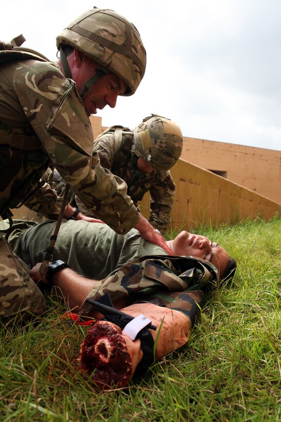 British Sgt. George P.H. Colquhoun (left),  a military intelligence operator and team medic for 7 Military Intelligence Battalion, 1 Intelligence Surveillance Reconnaissance Brigade, and native of Wallsend, England,  works alongside another British soldier  in caring for Sgt. Erick J. Velazquez (center), a geospatial intelligence analyst for 2nd Intelligence Battalion, II Marine Expeditionary Force, and a native of Coral Springs, Fla., as part of a casualty assessment and treatment scenario during Exercise Phoenix Odyssey on Sept. 16, 2014. The day’s training focused on common battlefield injuries, casualty care in the field, and lifesaving procedures in combat. The two forces have been training in a Military Operations in Urban Terrain facility on Camp Lejeune as part of a week long, scenario driven, bilateral exercise.