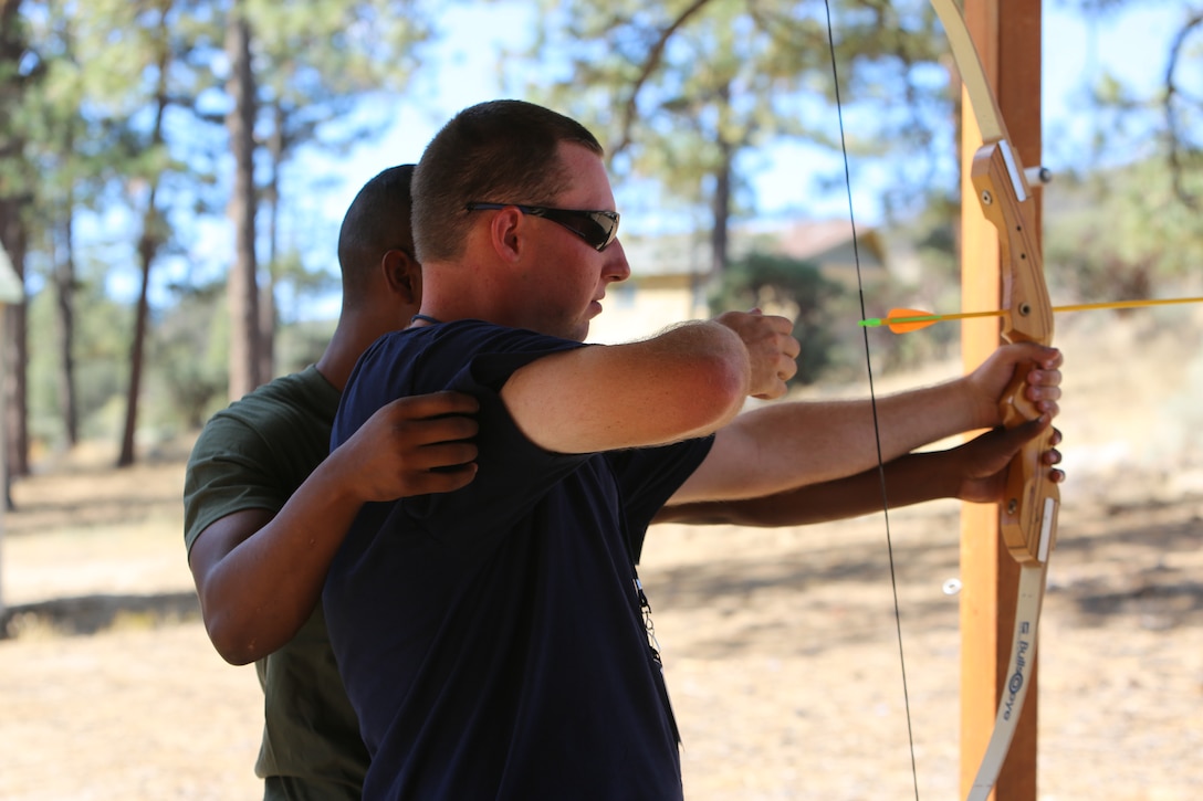 Lance Cpl. Carlos Morris, admin specialist, Headquarters Battalion, helps camper, Chase Neiberger learn how to shoot an archery bow at Camp Ronald McDonald in Mountain Center, Calif. on Sept. 13, 2014. 