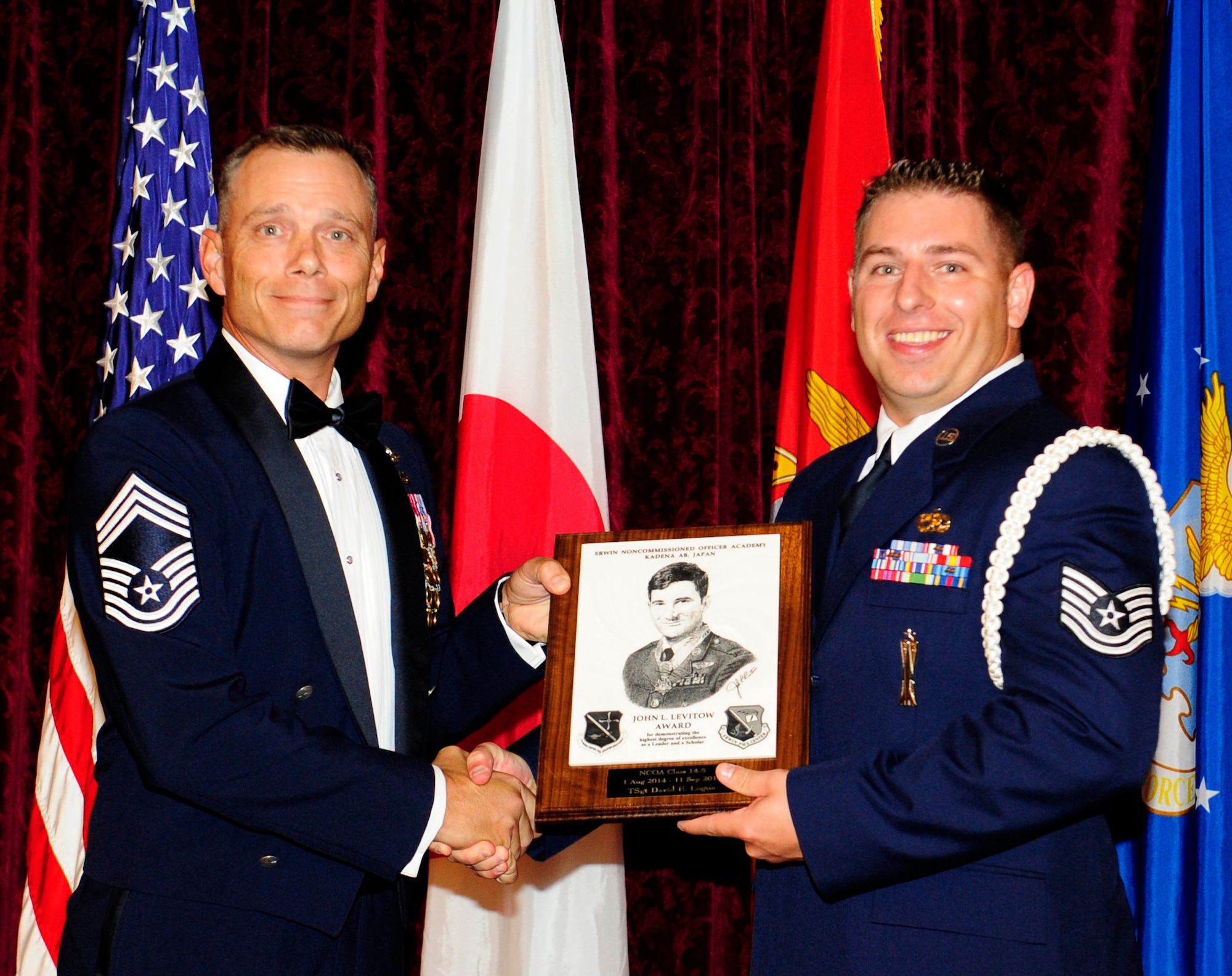 U.S. Air Force Chief Master Sgt. Erik Thompson, 353rd Special Operations Support Squadron superintendent and chief enlisted manager, presents Tech. Sgt. David Logue, 18th Munitions Squadron production supervisor, the John L. Levitow award during the NCO Academy Class 14-5/Airman Leadership School Class 14-F combined graduation ceremony at the NCO rocker club on Kadena Air Base, Japan, Sept. 11, 2014. This distinguished graduate award, named in memory of Medal of Honor recipient Airman 1st Class John L. Levitow, is presented to the most outstanding member of professional military education and denotes superior achievement as both a leader and a scholar. (U.S. Air Force photo by Airman 1st Class Keith James/Released)