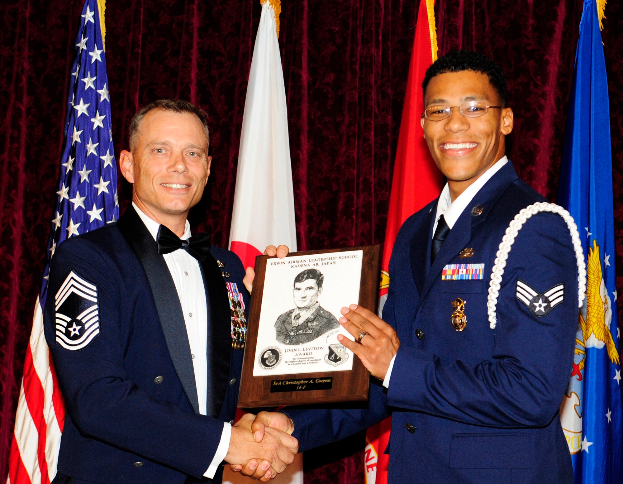 U.S. Air Force Chief Master Sgt. Erik Thompson, 353rd Special Operations Support Squadron superintendent and chief enlisted manager, presents Senior Airman Christopher Gwynn, 18th Security Forces response force leader, the John L. Levitow award during the NCO Academy Class 14-5/Airman Leadership School Class 14-F combined graduation ceremony at the NCO rocker club on Kadena Air Base, Japan, Sept. 11, 2014. This distinguished graduate award, named in memory of Medal of Honor recipient Airman 1st Class John L. Levitow, is presented to the most outstanding member of professional military education and denotes superior achievement as both a leader and a scholar. (U.S. Air Force photo by Airman 1st Class Keith James/Released)