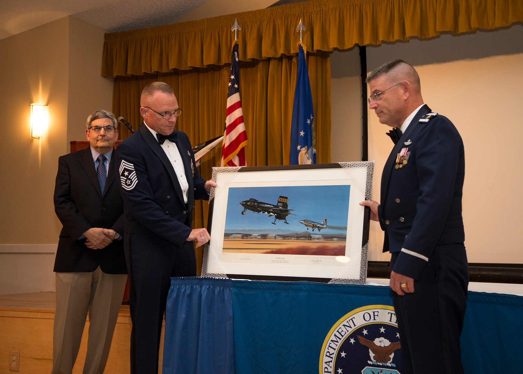 Chief Master Sgt. Brian Randolph (center), 412th Test Wing command chief, unveils a new painting from renowned aviation artist Mike Machat (back) who presented the painted of the X-15 to Team Edwards in honor of the Air Force's birthday. (U.S. Air Force photo by Bobbi Zapka)