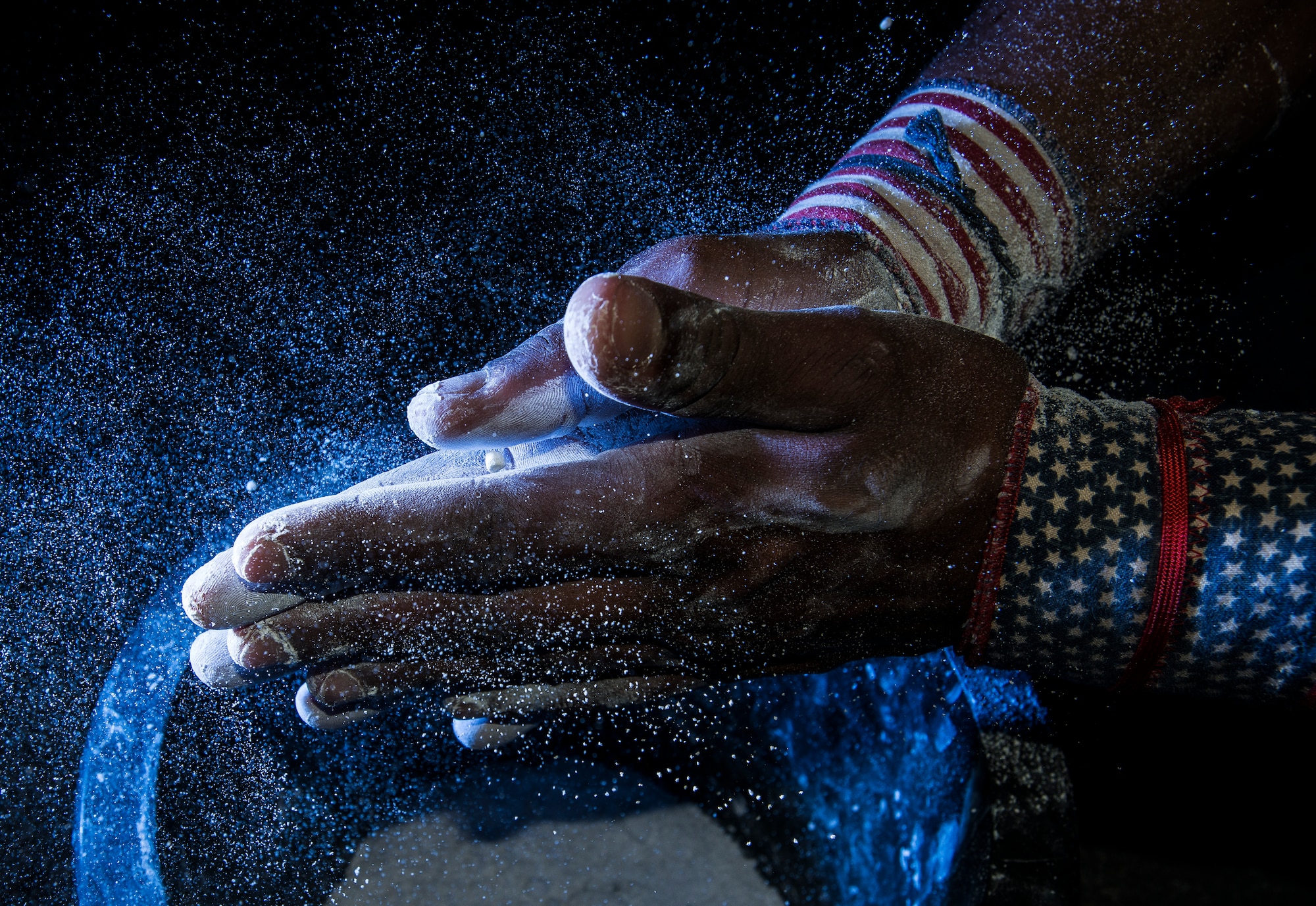 Senior Airman Jacob Allen, 437th Aircraft Maintenance Squadron crew chief, rubs chalk on his hands before performing butterfly pull-ups during a CrossFit class Sept. 16, 2014, at the Joint Base Charleston Fitness Center. Individuals perform several repetitions of each exercise as they progress through their workout. (U.S. Air Force photo/ Senior Airman Dennis Sloan)