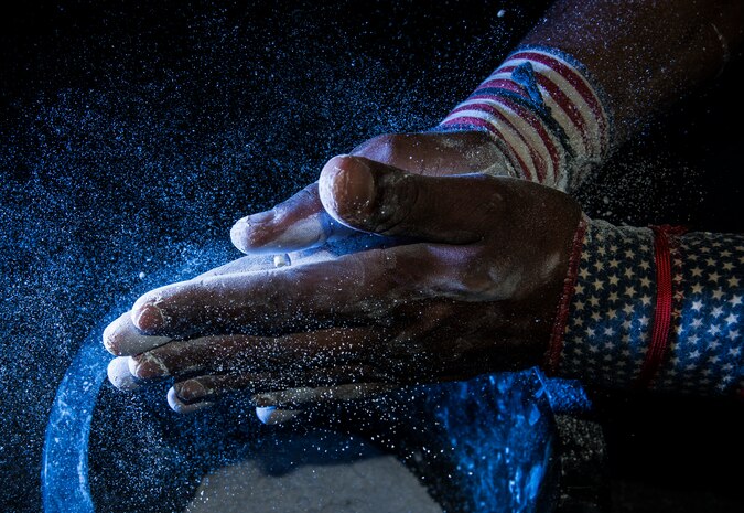 Senior Airman Jacob Allen, 437th Aircraft Maintenance Squadron crew chief, rubs chalk on his hands before performing butterfly pull-ups during a CrossFit class Sept. 16, 2014, at the Joint Base Charleston Fitness Center. Individuals perform several repetitions of each exercise as they progress through their workout. (U.S. Air Force photo/ Senior Airman Dennis Sloan)