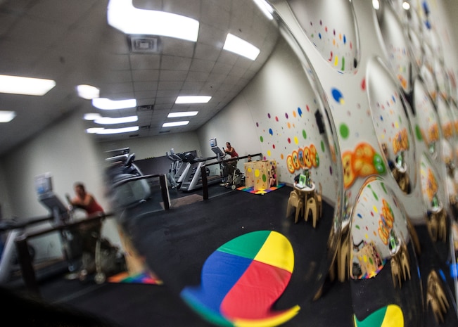 Military spouses use cardio machines while their children utilize the playroom, Sept. 16, 2014, at the Joint Base Charleston Fitness Center. The Fitness and Sports Center services more than 1,000 customers daily. (U.S. Air Force photo/ Senior Airman Dennis Sloan)