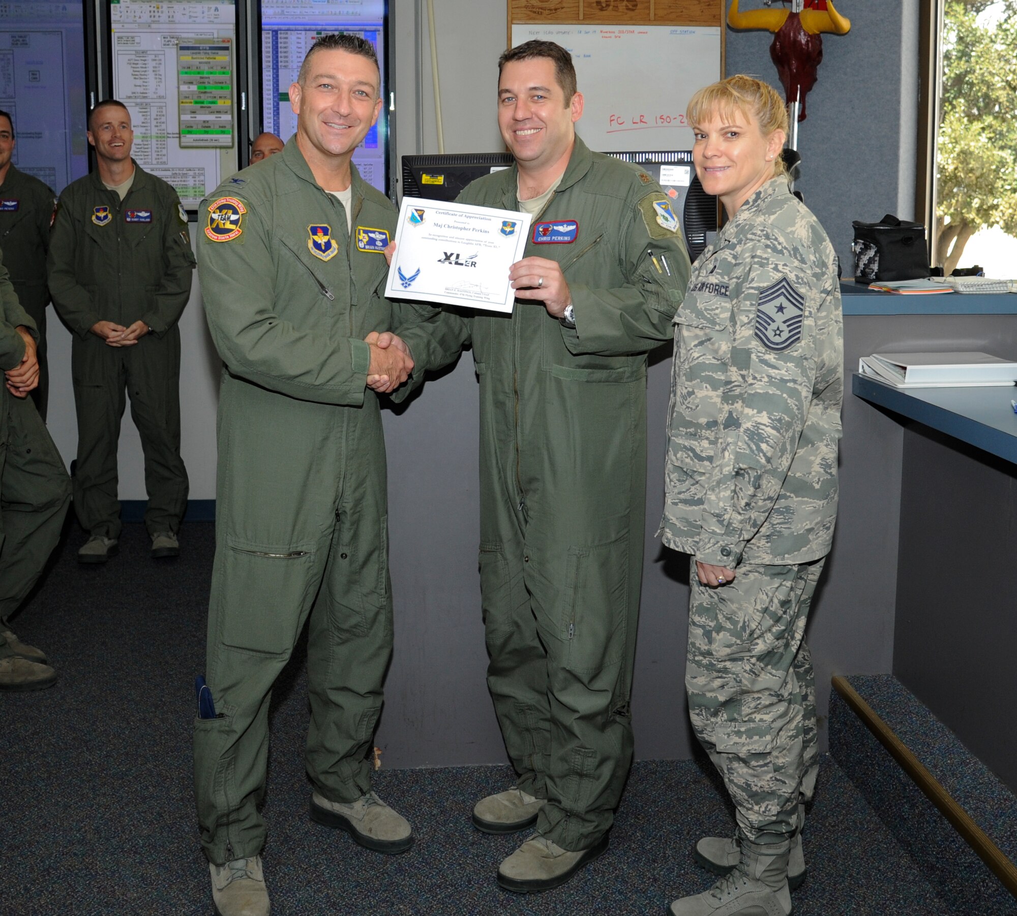 Maj. Christopher Perkins, center, 87th Flying Training Squadron assistant director of operations, poses with Col. Brian Hastings, left, 47th Flying Training Wing commander, and Chief Master Sgt. Teresa Clapper, right, 47th FTW command chief, after being presented the XLer of the week award here Sept. 17, 2014. The XLer is a weekly award chosen by wing leadership and given to those who consistently make outstanding contributions to their unit and Laughlin. (U.S. Air Force photo by Airman 1st Class Jimmie D. Pike)(Released)