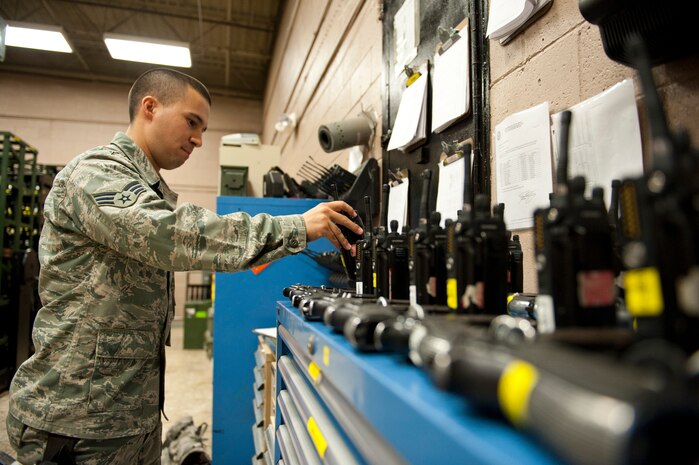 Senior Airman Ian Bonilla, 99th Security Forces Squadron armorer, prepares M-9 pistols and radios at the armory for members of the incoming shift, Nellis Air Force Base, Nev., Sept. 16, 2014. The armory is responsible for storing, cleaning, and maintaining an inventory of more than 580 M-9 pistols. (U.S. Air Force photo by Airman 1st Class Thomas Spangler)