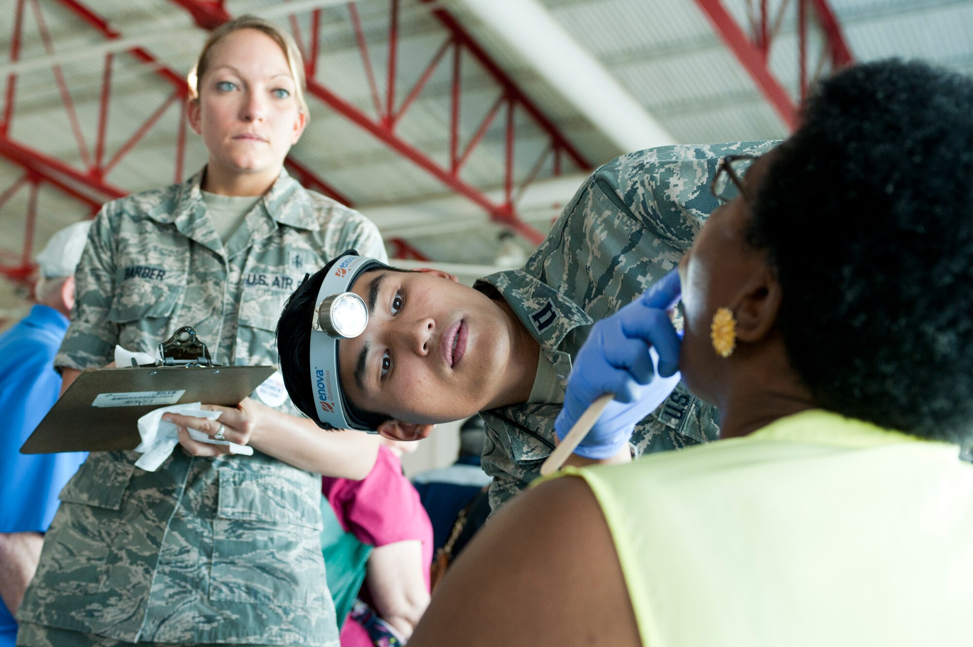 U.S. Air Force Capt. Khiem Nguyen, 99th Dental Squadron Advanced Education in General Dentistry resident, examines a patients mouth while U.S. Air Force Staff Sgt. Sagan Barber, 99th DS Dental Clinic technician, takes down information during a Retiree Appreciation Day information fair at Nellis Air Force Base, Nev., Sept. 13, 2014. The information fair offered opportunities for attendees to consult medical professionals for advice and schedule future treatment. (U.S. Air Force photo by Senior Airman Timothy Young)  