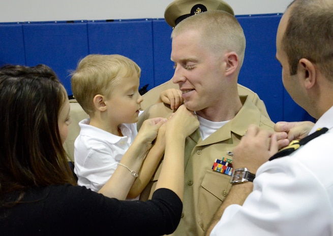 Chief Petty Officer Robert Mostrom, has his anchors pinned on by his wife and son during the Naval Nuclear Power Training Command Chief's Pinning Ceremony Sept. 16, 2014, in the Rickover Memorial Auditorium on Joint Base Charleston, S.C. NNPTC pinned 22 new chief petty officers. (U.S. Air Force photo/Petty Officer 2nd Class Jason Pastrick)