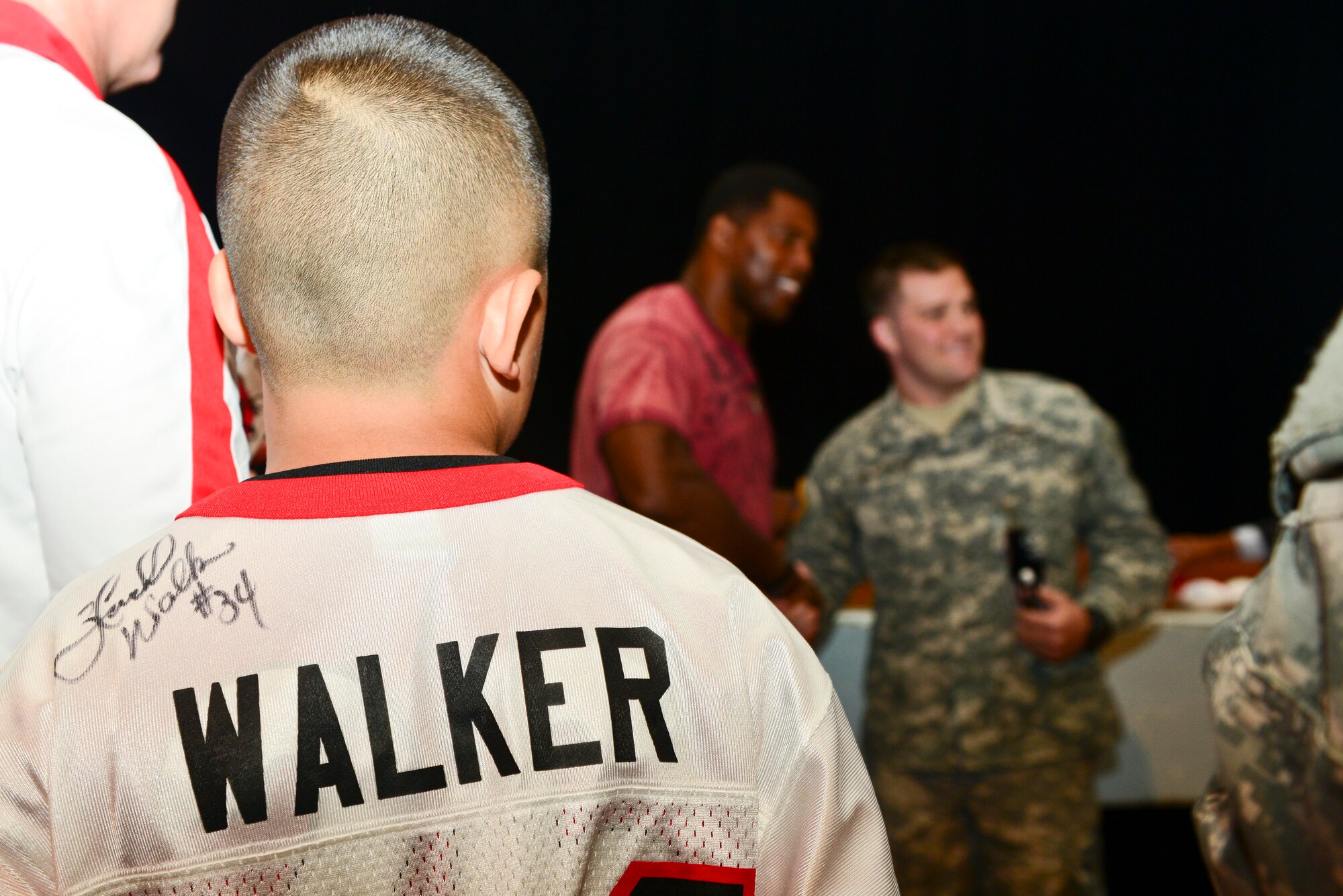 Andy Anderson and his father, James Anderson, local U.S. Army retiree, wait in line to get a photo with and autograph from Herschel Walker, Heisman Trophy recipient and mental health advocate, at Fort Eustis, Va., Sept. 16, 2014. During his visit, Walker encouraged U.S. Service members to ask for help for mental health and substance abuse issues. (U.S. Air Force photo by Airman 1st Class Kimberly Nagle/Released) 