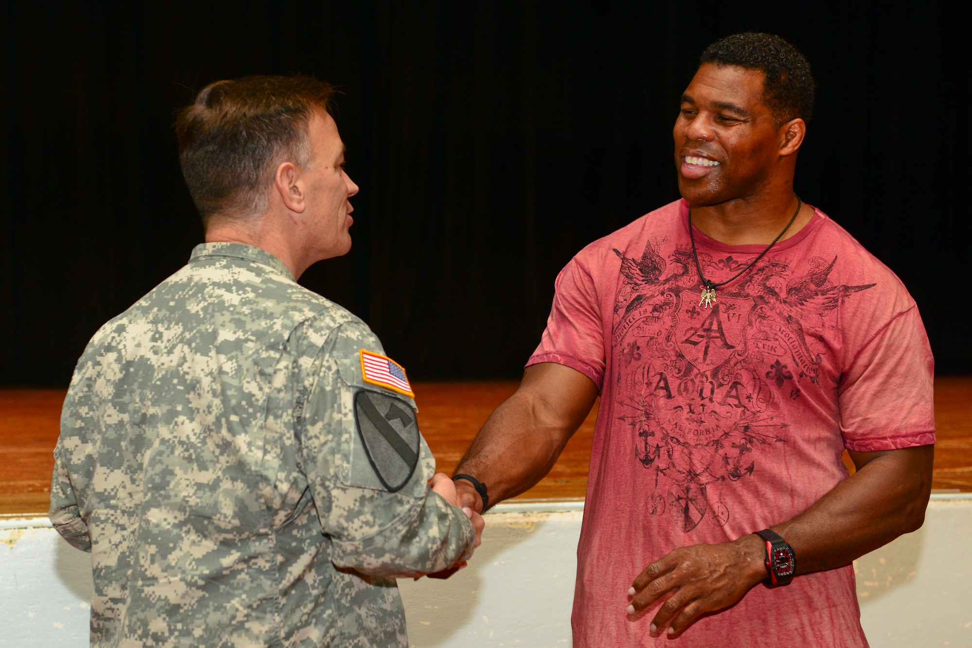 Herschel Walker, Heisman Trophy recipient and mental health advocate, receives a coin from U.S. Army Col. William Galbraith, 733rd Mission Support Group commander, after speaking to a crowd at Fort Eustis, Va., Sept. 16, 2014. Walker is a spokesperson for programs specialized in mental health and addiction treatment for Service members, and has visited more than 80 military installations sharing his story. (U.S. Air Force photo by Airman 1st Class Kimberly Nagle/Released) 