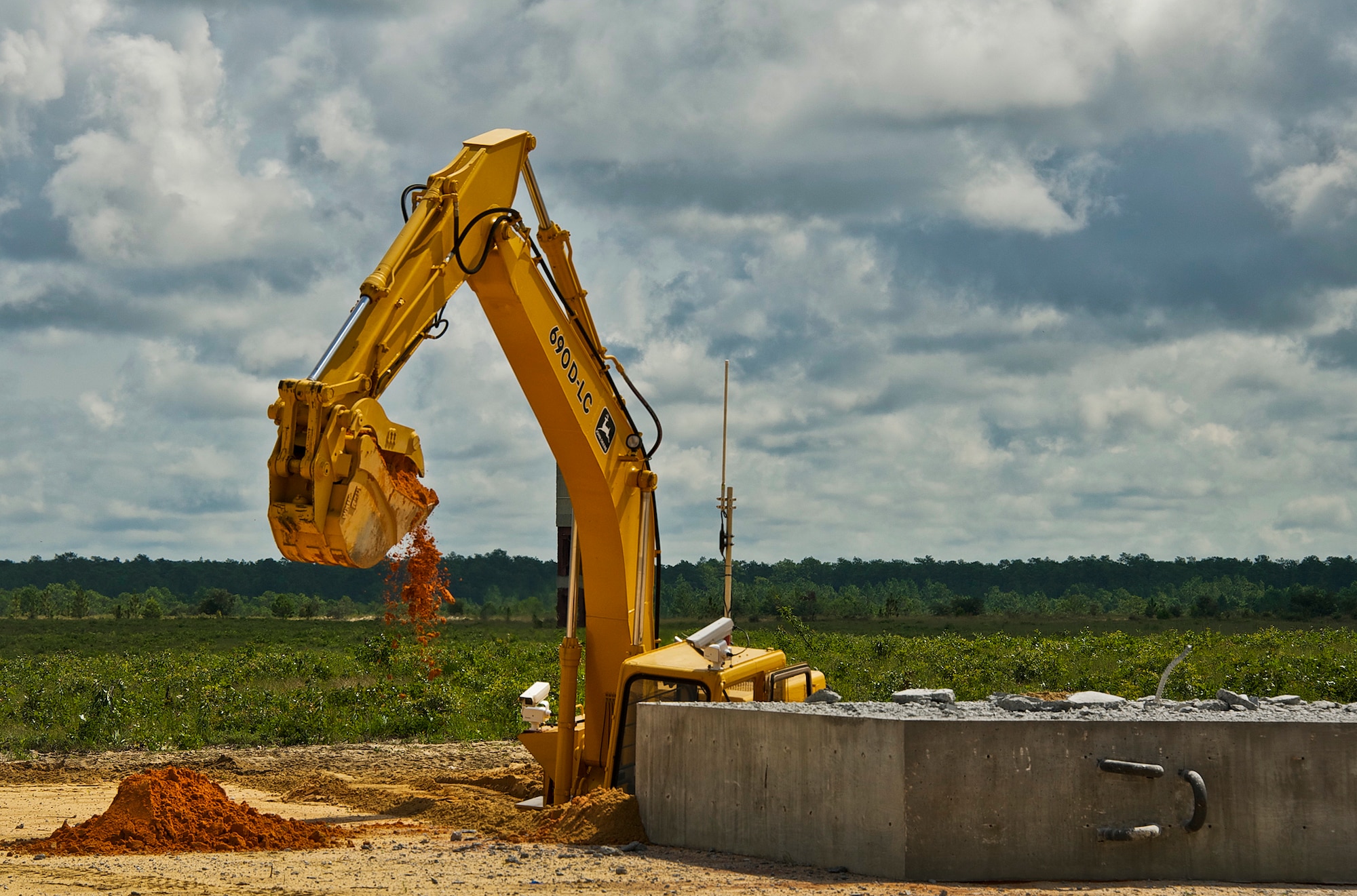 A 96th Civil Engineer Squadron robotics team member manually operates a large robotic excavator, the “John Deere 690D,” before leaving it to remotely dig via operators in a trailer a safe distance away from the test site Sept. 9. Their modified vehicles are designed for remote manipulation of hazardous items using hydraulically actuated “arm” manipulators.  The arms have reasonably high dexterity, enough to use a screwdriver and other tools, while having enough power to roll a car.  The controllers for the robotic arms follow along the operator’s arm virtually in a trailer set approximately a mile from the site for safety. (U.S. Air Force photo/Chrissy Cuttita)