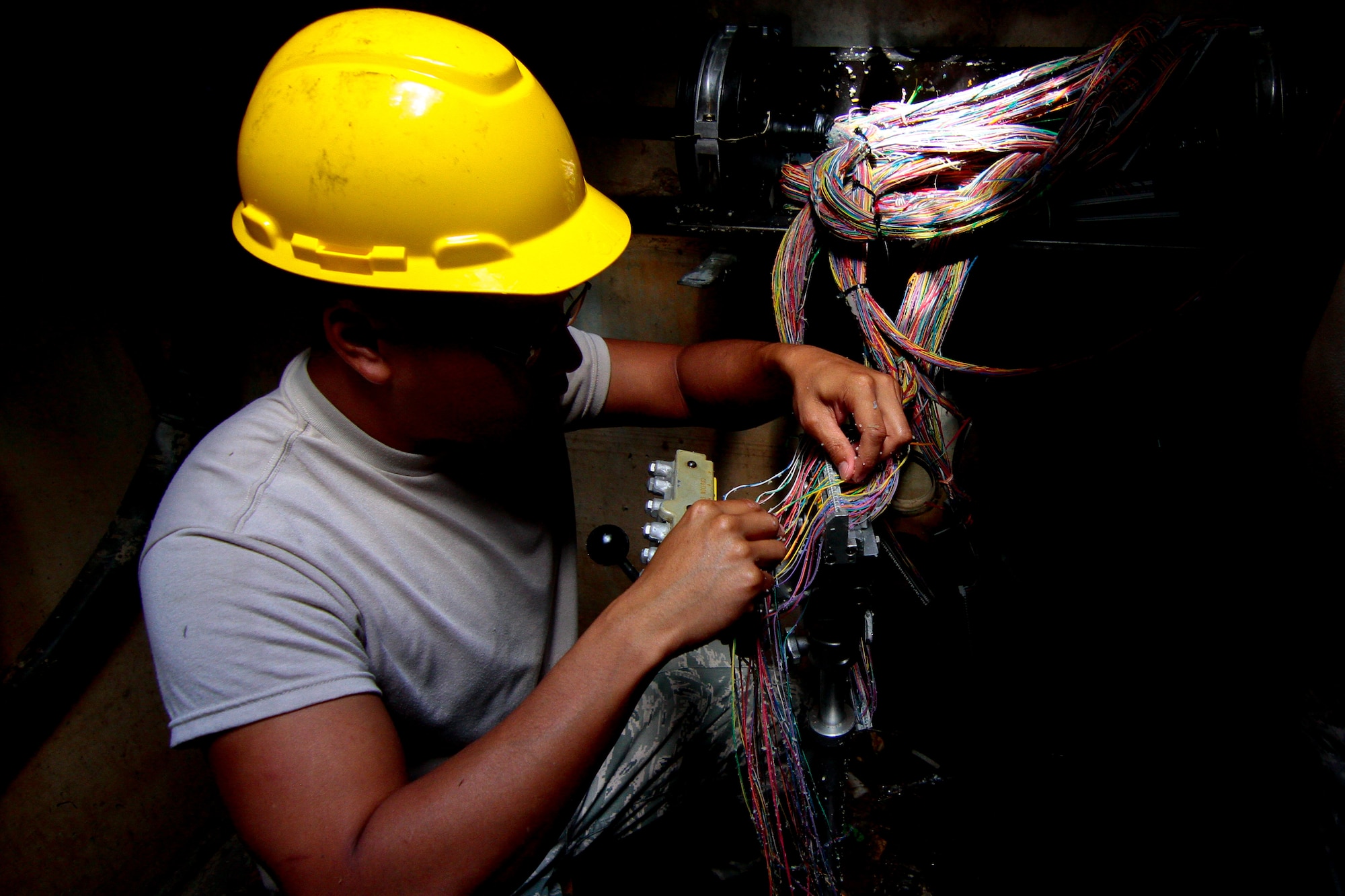 A picture of an Airman from the 212th Engineering Installation Squadron splicing wires in a manhole.