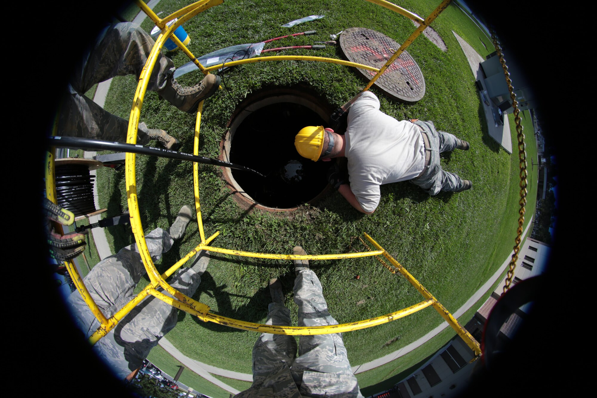 A picture of U.S. Air Force Senior Airman Mike Davies from the 212th Engineering Installation Squadron looking into an underground conduit.