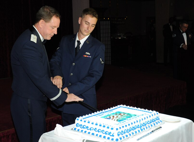 U.S. Air Force Brig. Gen. James Hecker, 18th Wing commander, and Airman Kevin O'Leary, 18th Equipment Maintenance Squadron, cut the Air Force's birthday cake with a saber during the 2014 Air Force Ball on Kadena Air Base, Japan, Sept. 13, 2014. Keeping with tradition, a slice of cake is given to the most senior ranking and junior ranking Airmen to signify respect and honor afforded to experience and seniority while symbolizing how our experienced Airmen have nurtured and led young Airmen to fill the ranks. (U.S. Air Force photo by Airman 1st Class Zackary A. Henry/Released)